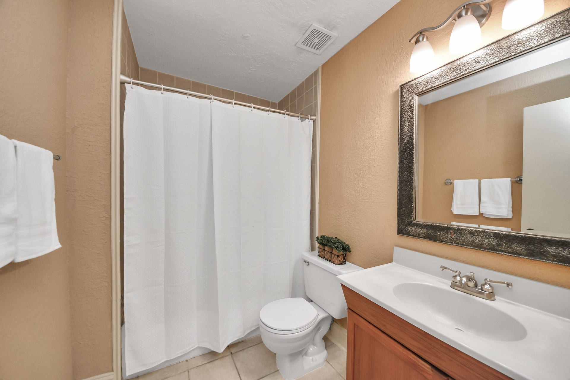 935 Grand Junction Drive, Katy, TX 77450 The upper-level full bathroom offers a welcoming combination of comfort and practicality. Warm neutral walls complement the wood-tone vanity, while a spacious countertop, decorative framed mirror, and multi-light vanity fixture add character to the space.