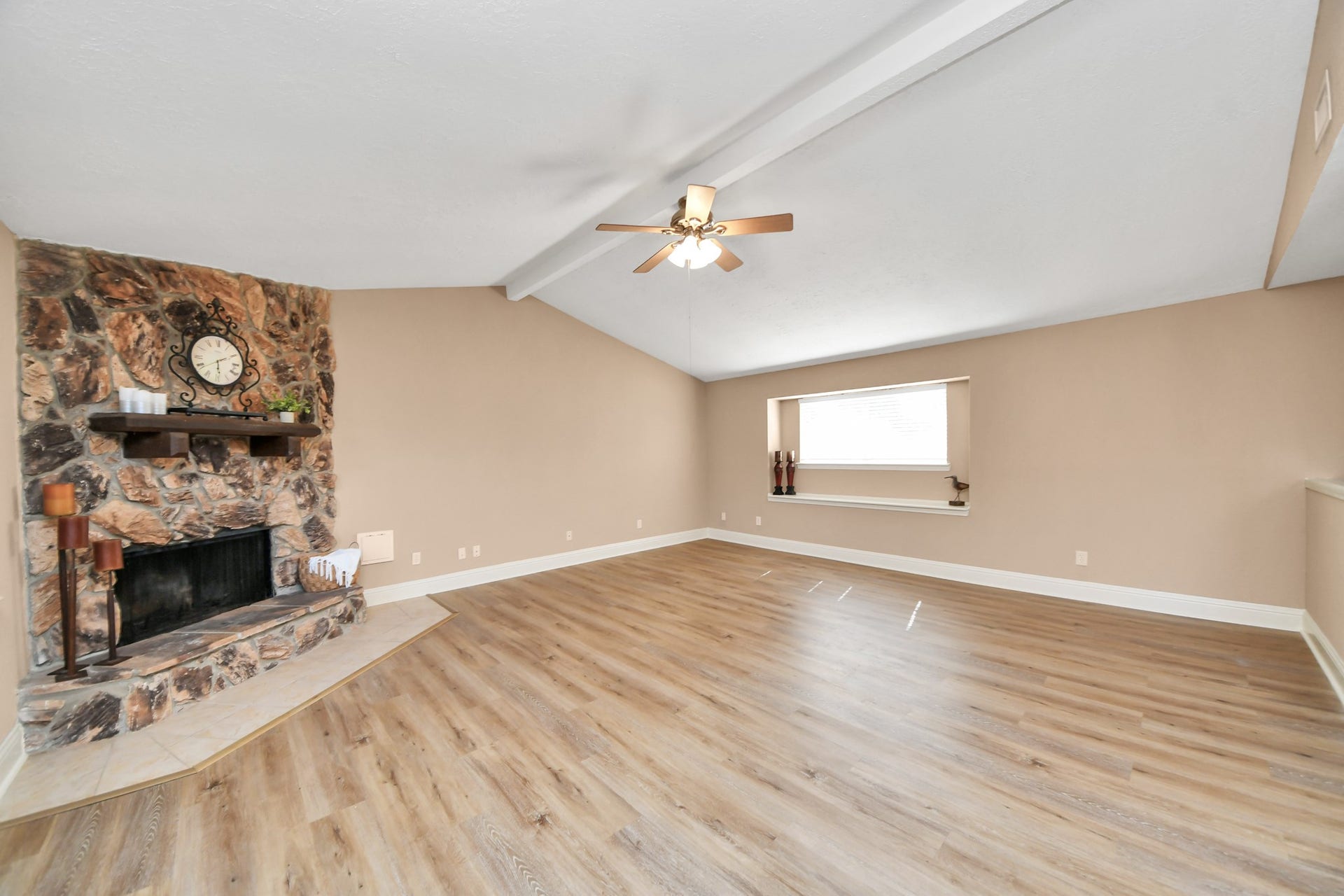 935 Grand Junction Drive, Katy, TX 77450 This beautiful living room features a dramatic vaulted ceiling, exposed beam detail, and a striking natural stone fireplace.