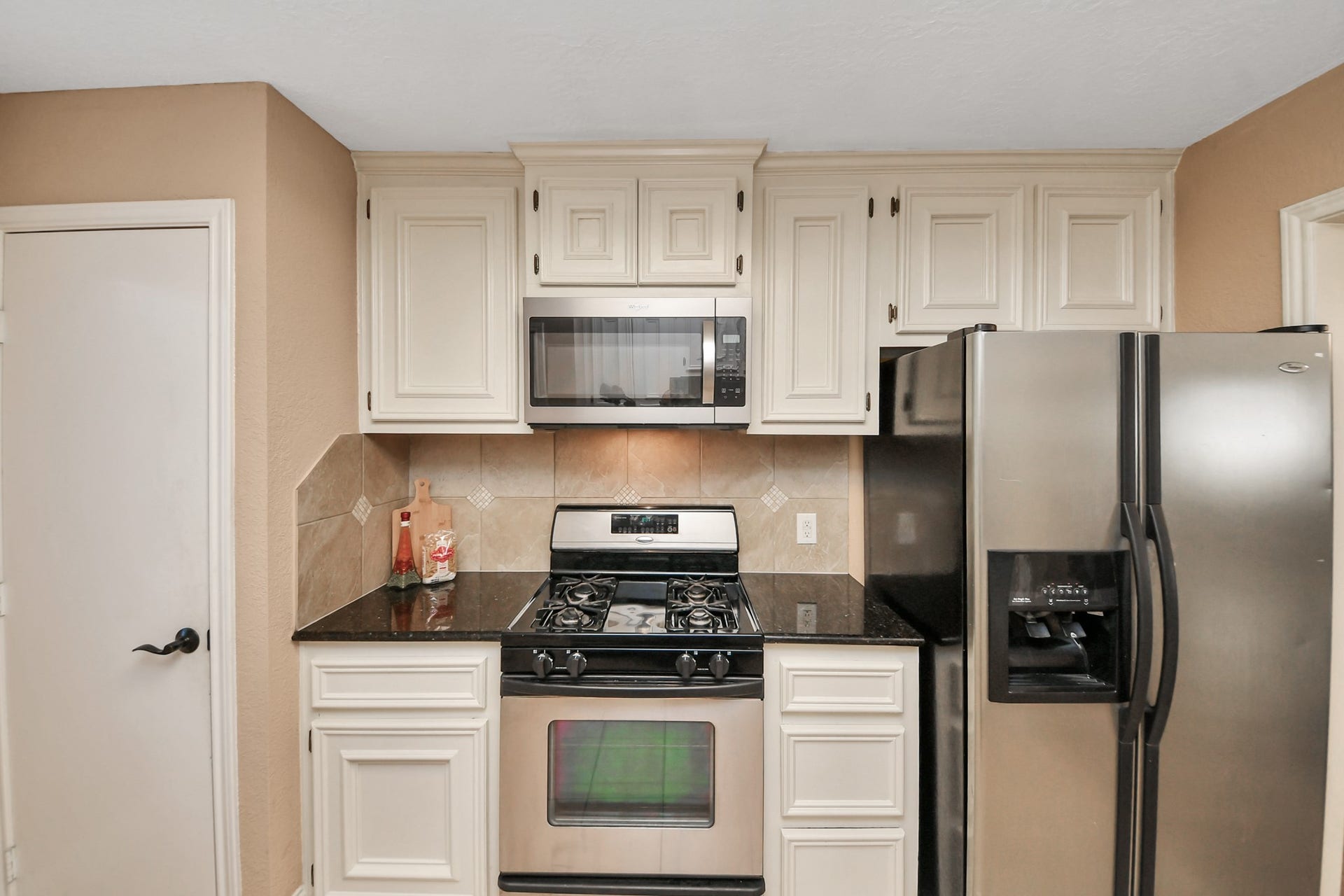 935 Grand Junction Drive, Katy, TX 77450 Stainless steel appliances, including a gas range, built-in microwave, and side-by-side refrigerator with an exterior water and ice dispenser, complete the space.