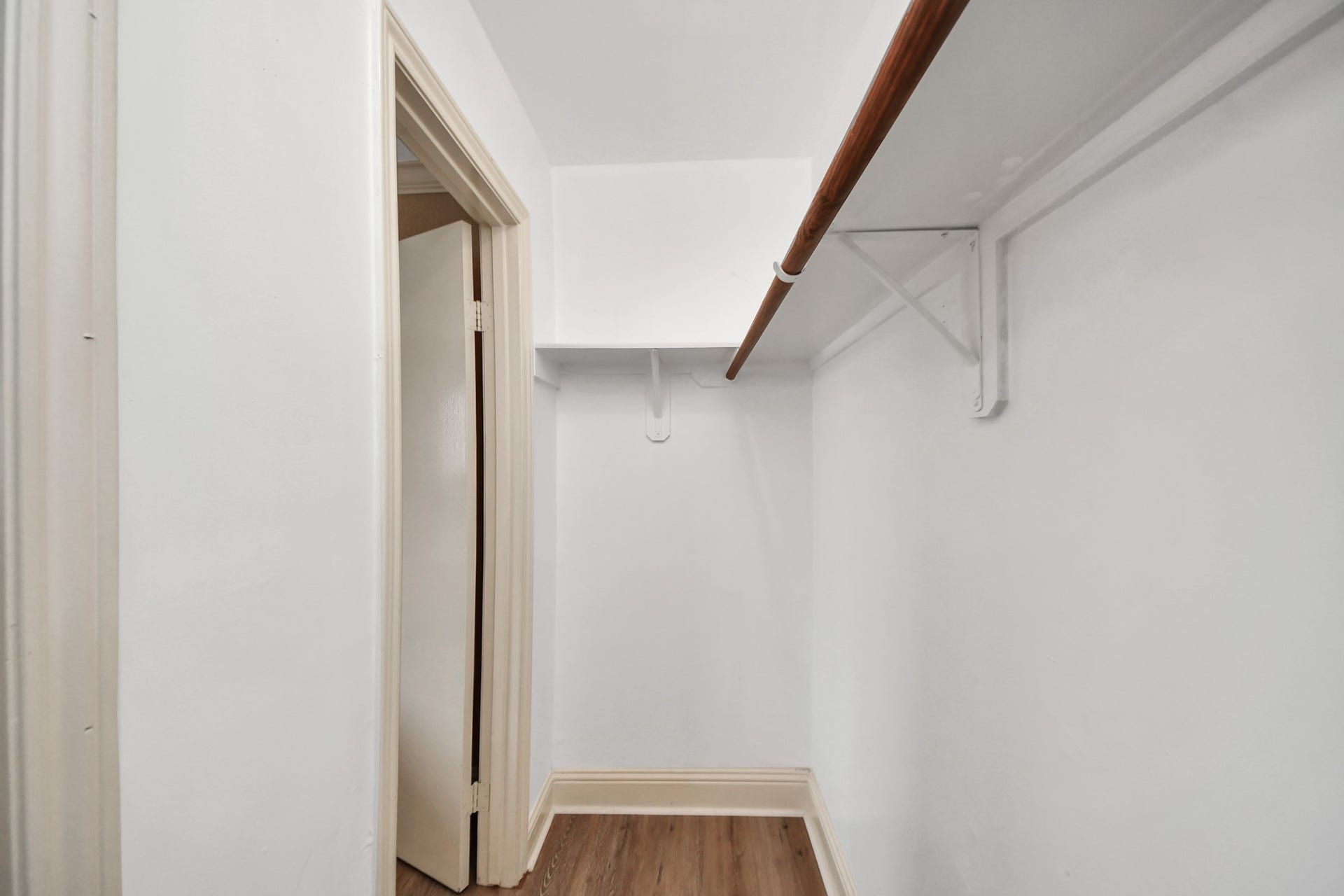935 Grand Junction Drive, Katy, TX 77450 White walls provide a clean, bright appearance, while the built-in hanging rods and overhead shelving offer room for clothing, shoes, and accessories. The wood-look flooring continues into the closet, creating a cohesive transition from the bedroom.