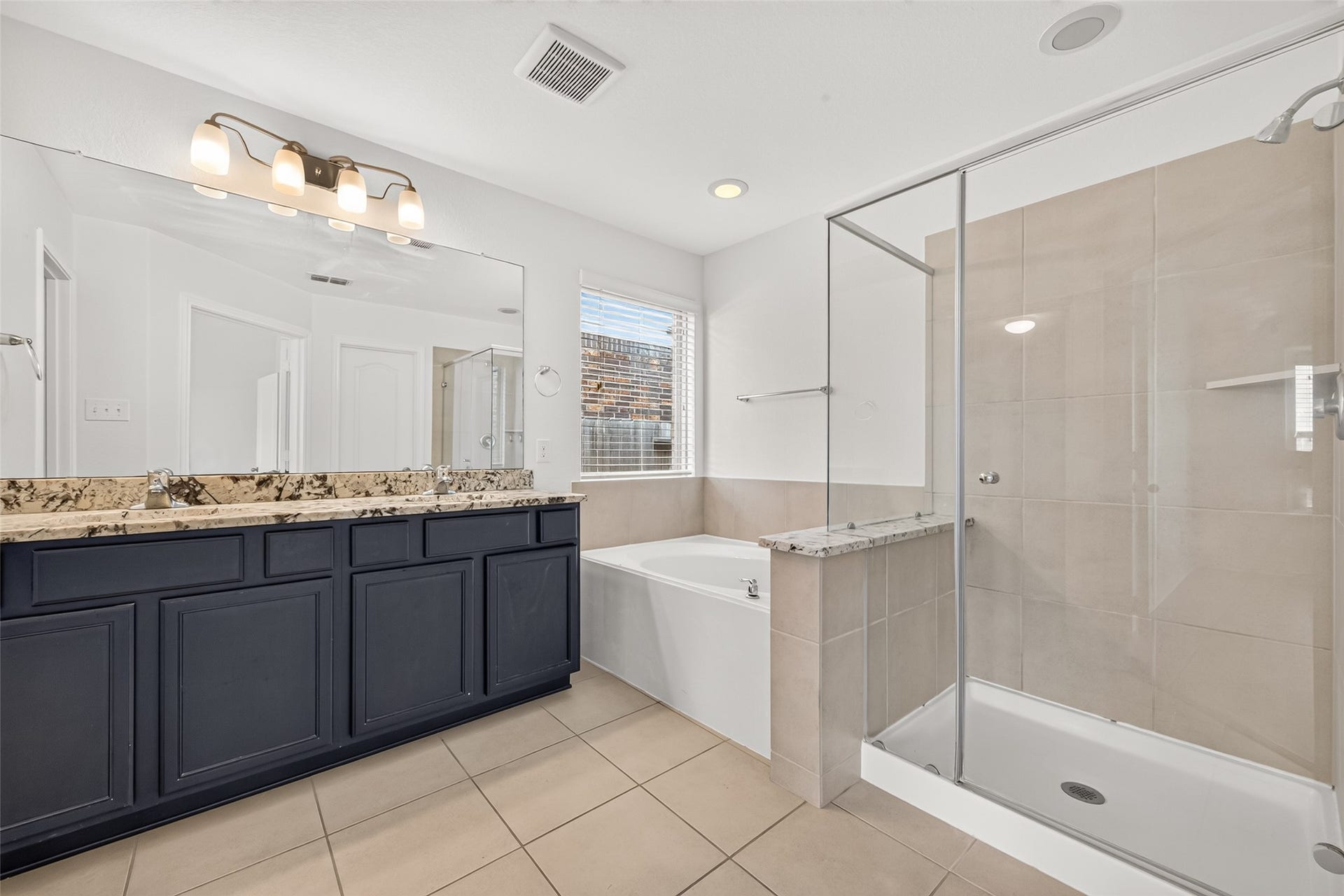 Primary bathroom with double sinks, soaking tub, and separate shower