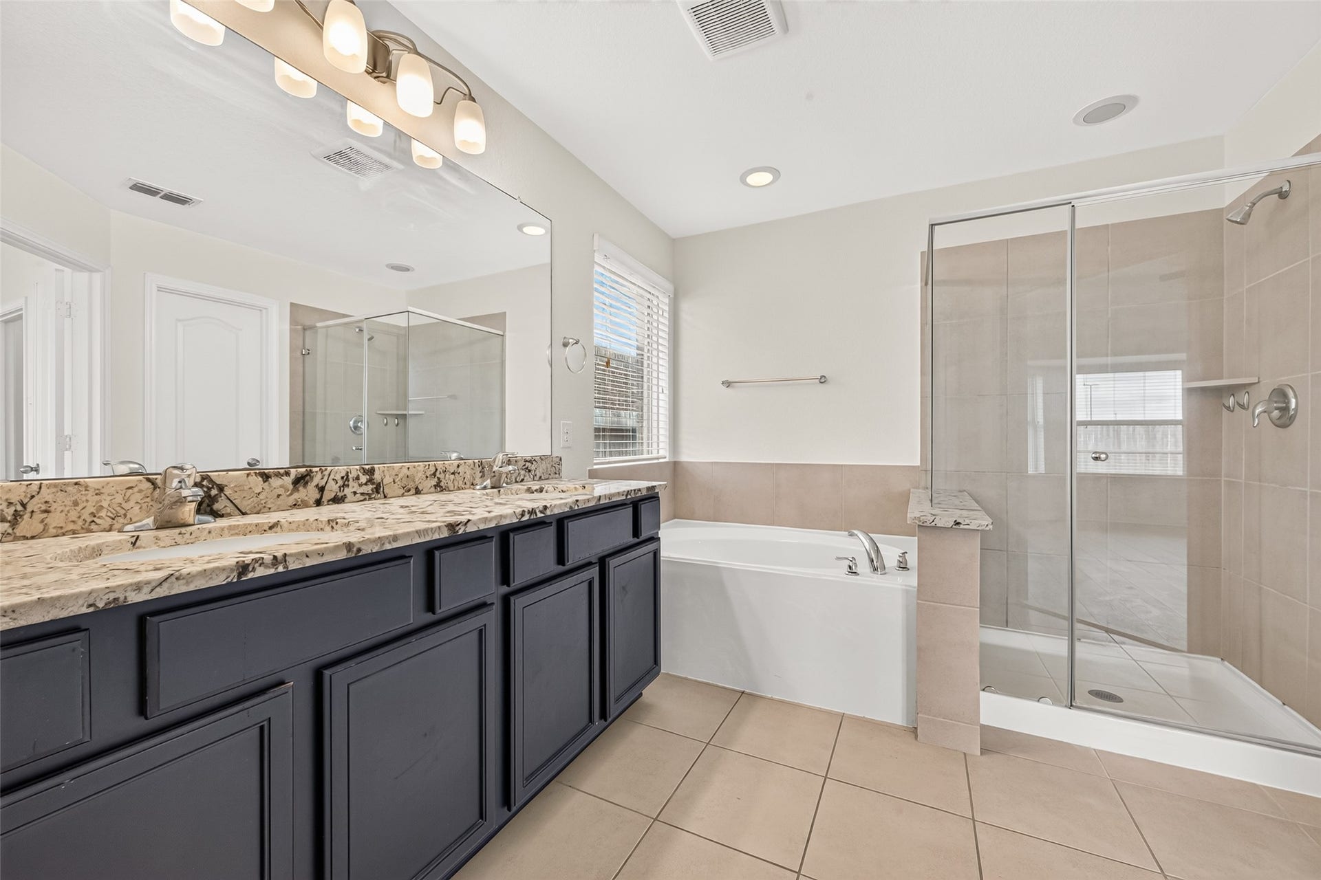 Primary bathroom with double sinks, soaking tub, and separate shower