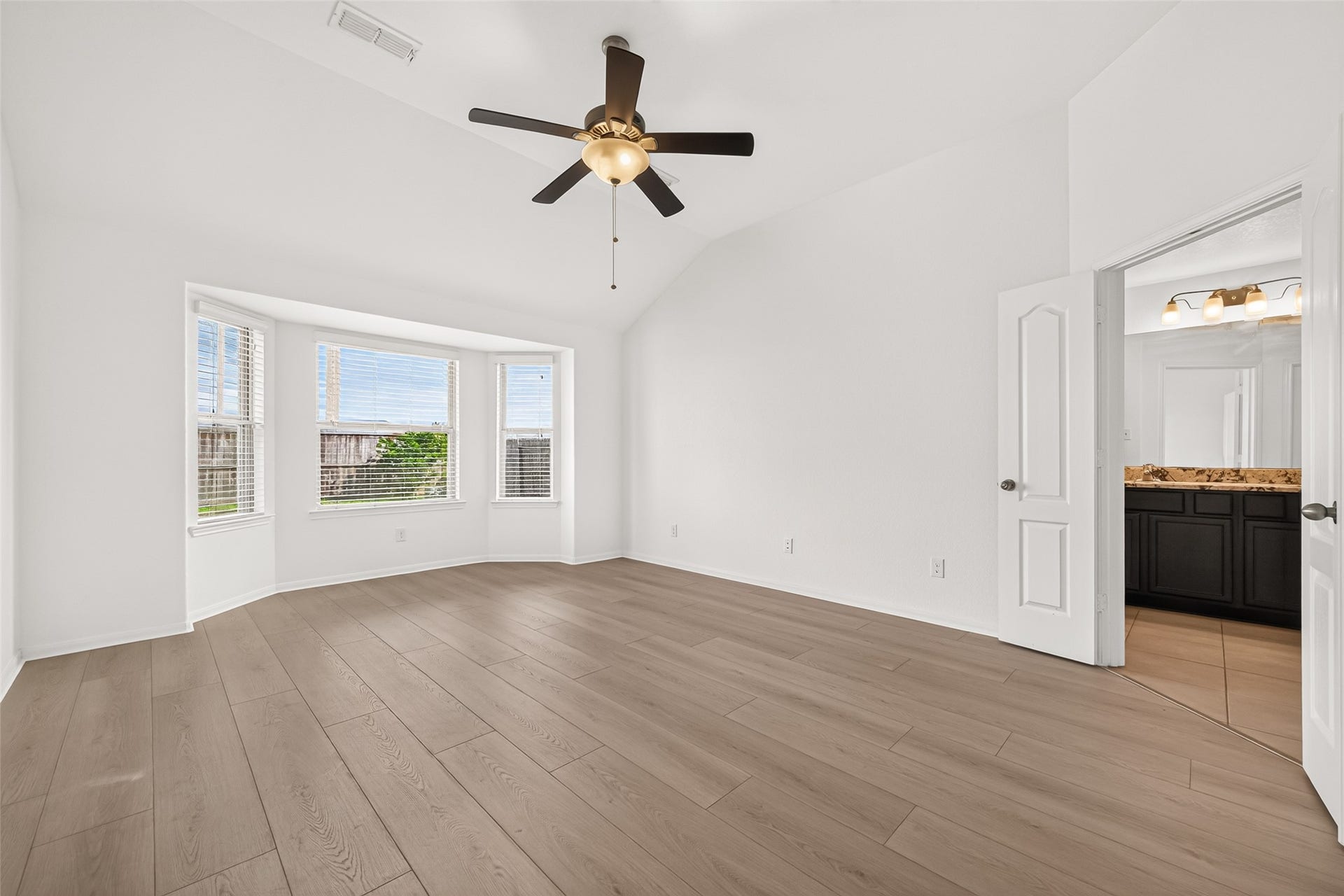 Primary bedroom has new wood look flooring and fresh paint. Features include the bay window and ceiling fan to keep cool during these Texas summers!