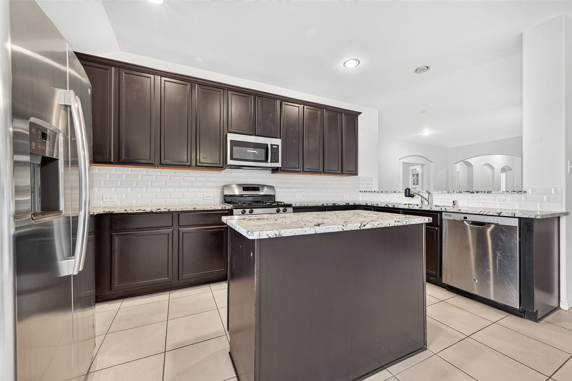 Kitchen with beautiful granite countertops and sleek dark cabinets is equipped with stainless steel appliances (refrigerator included).