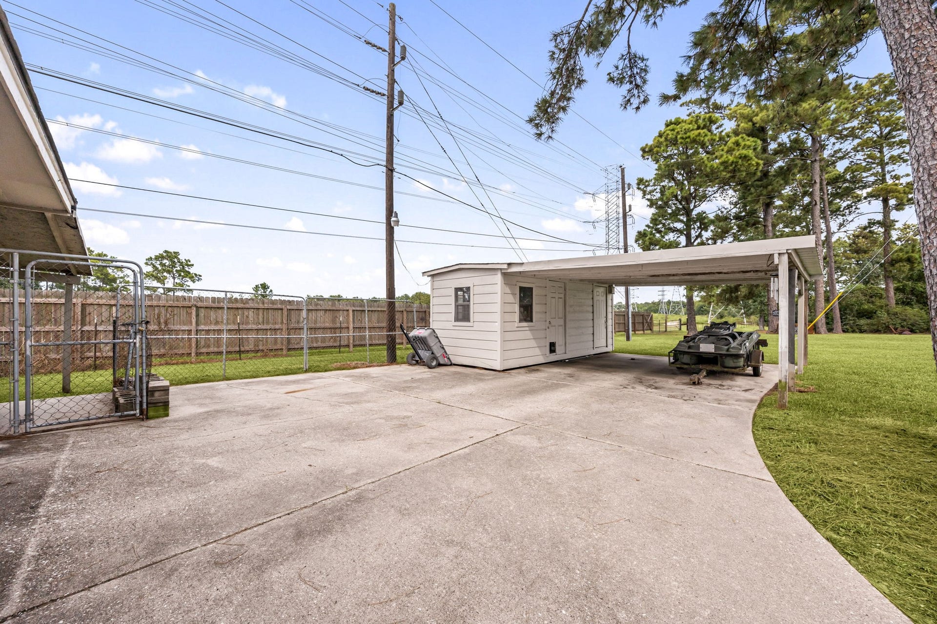 Wide-open outdoor space with driveway access leading toward the detached garage and workshop.