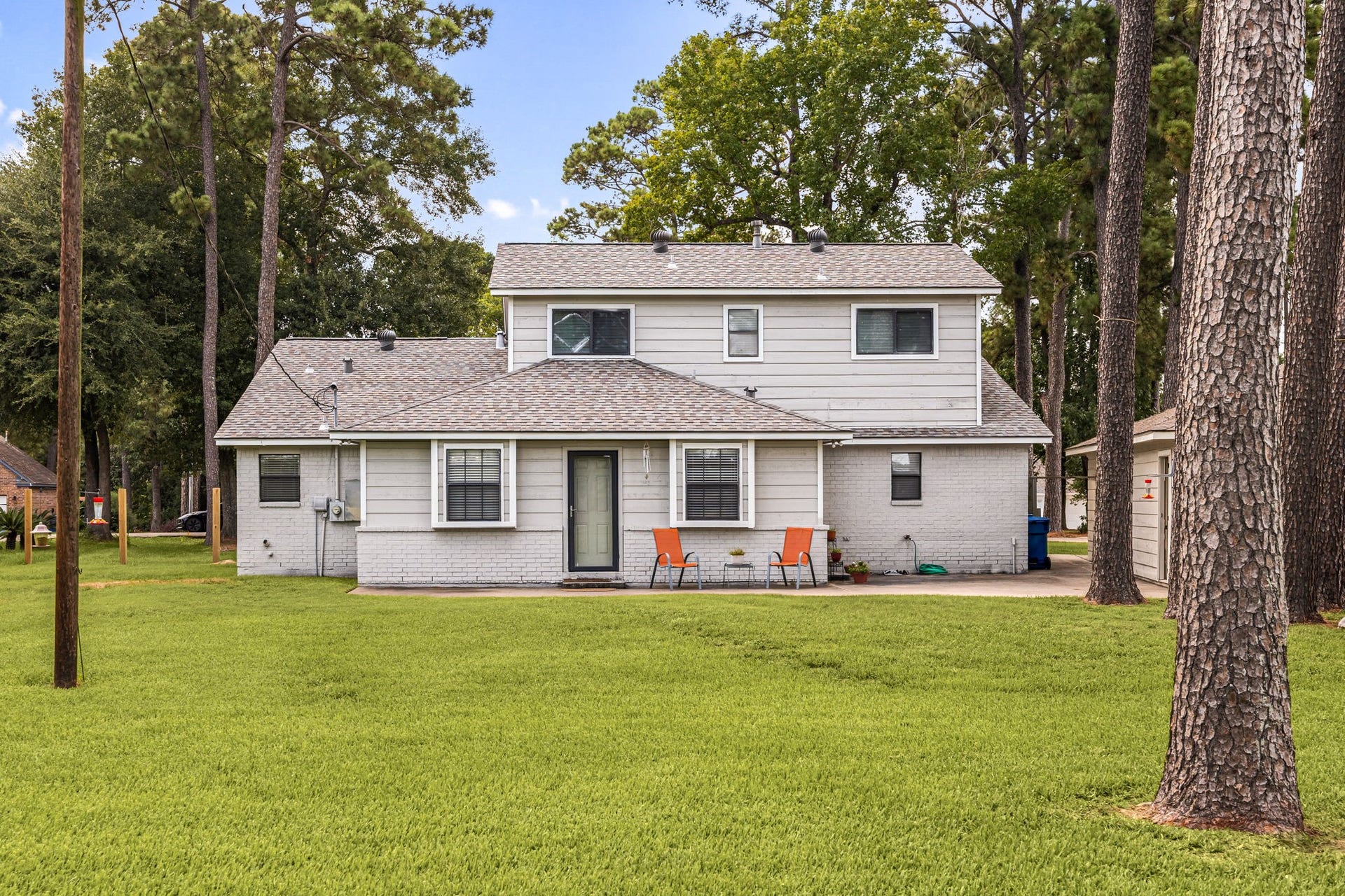 Large backyard provides an abundance of open green space surrounded by mature trees.