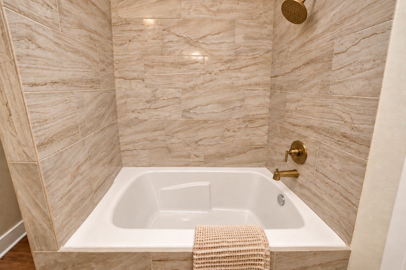 6675 Nielan Street, Houston, TX 77028 Close-up of the primary bathroom's soaking tub and shower combination, featuring beautiful floor-to-ceiling tile, elegant gold-tone fixtures & a spacious bathing area.