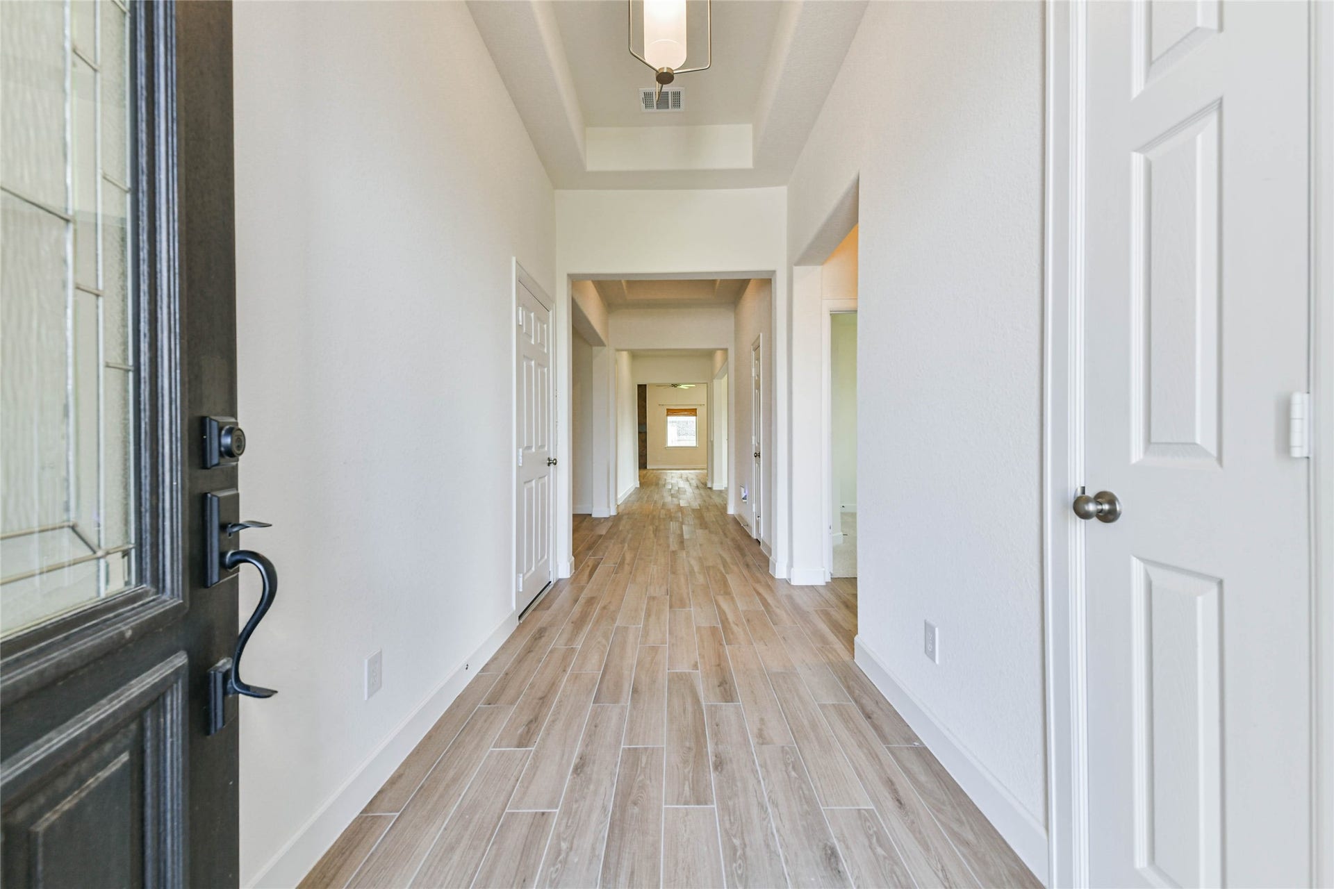 702 Campbell Drive, League City, TX 77573 Step into a bright and inviting hallway with elegant wood-look tile flooring, leading to spacious living areas.