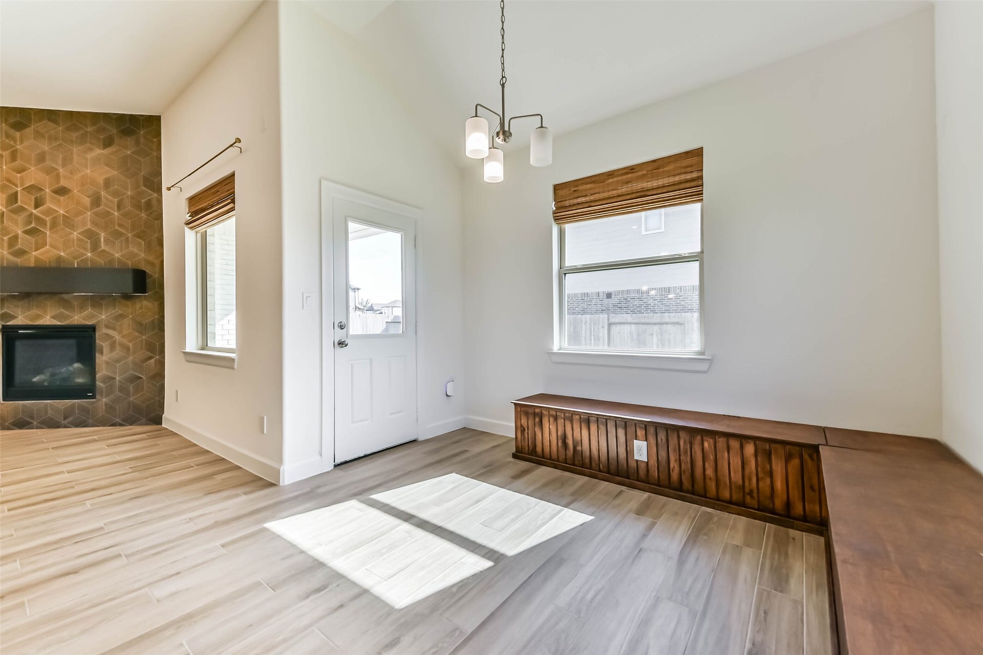 702 Campbell Drive, League City, TX 77573 Bright and inviting living space featuring a stylish geometric accent wall with a cozy fireplace, elegant wooden bench seating, and abundant natural light.