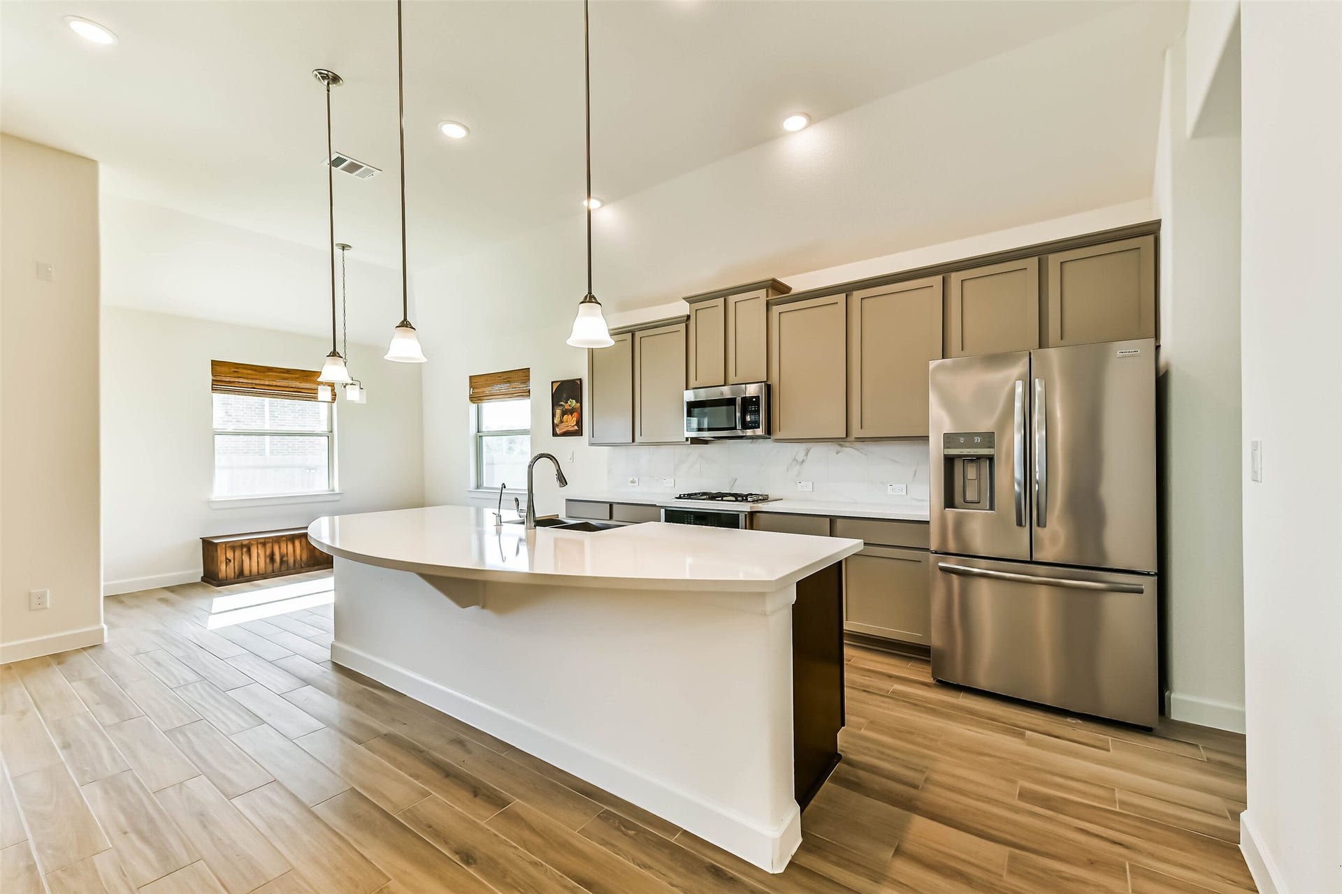 702 Campbell Drive, League City, TX 77573 Bright, modern kitchen featuring a sleek island with pendant lighting, stainless steel appliances, and ample cabinet space, seamlessly connected to an inviting dining area with natural light.