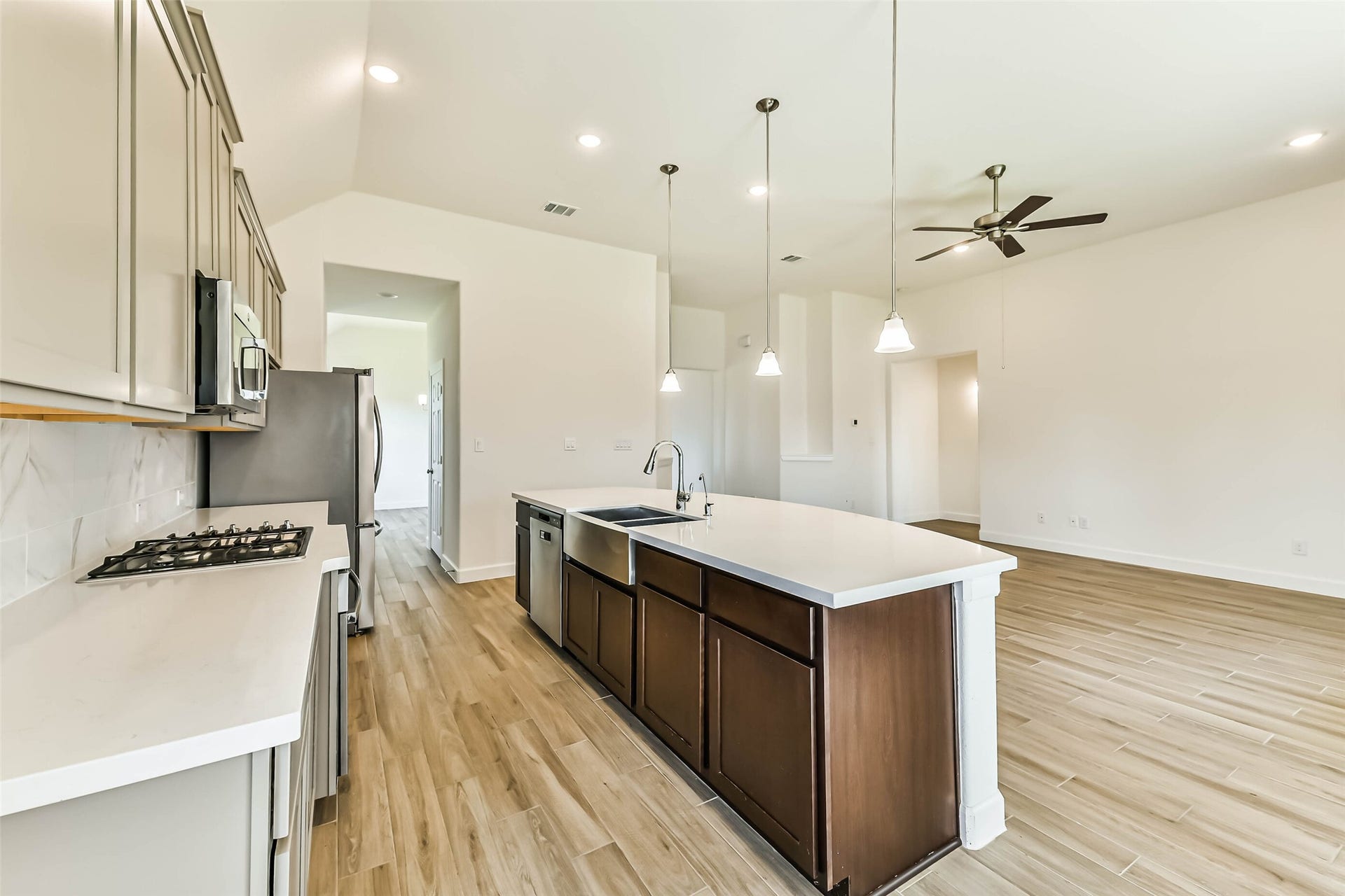 702 Campbell Drive, League City, TX 77573 Modern kitchen with sleek countertops, stainless steel appliances, and an open layout flowing into a spacious living area with high ceilings and stylish lighting.
