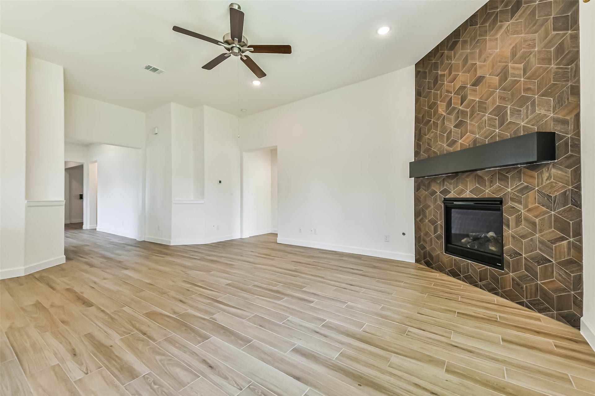 702 Campbell Drive, League City, TX 77573 Spacious living area featuring elegant wood-look tile flooring and a striking geometric accent wall with a modern fireplace.