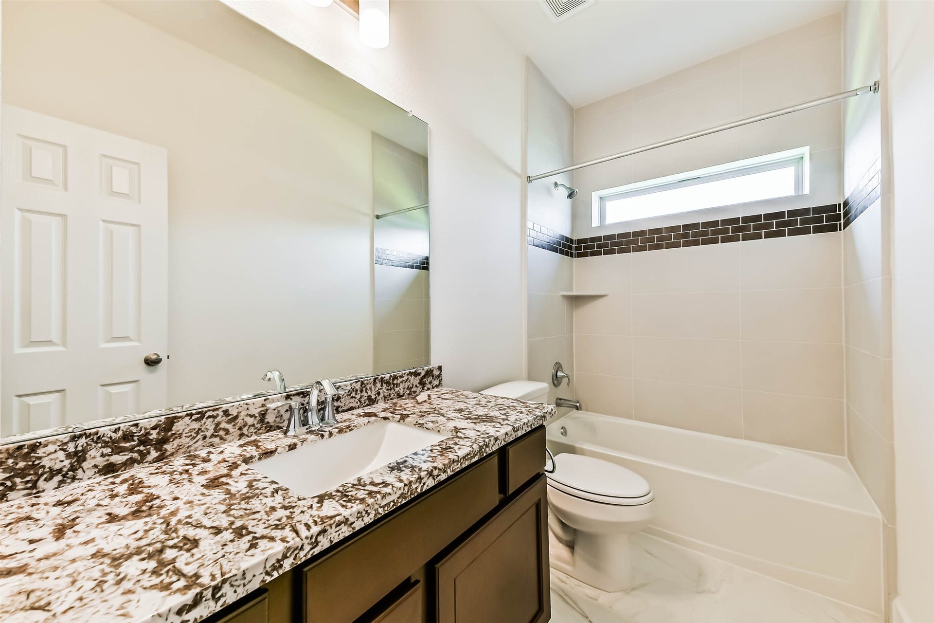 702 Campbell Drive, League City, TX 77573 Seccondary Modern bathroom #2 featuring a sleek granite countertop, elegant fixtures, and a stylish tiled bathtub with accent trim.