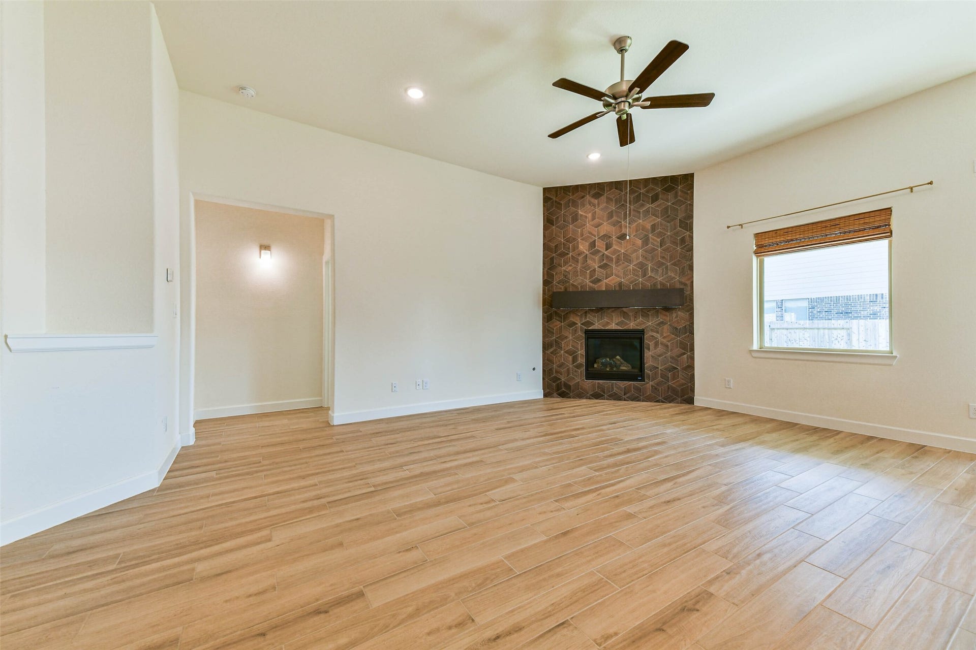 702 Campbell Drive, League City, TX 77573 Spacious living room with a modern fireplace, elegant wood-style flooring, and ample natural light from a large window.