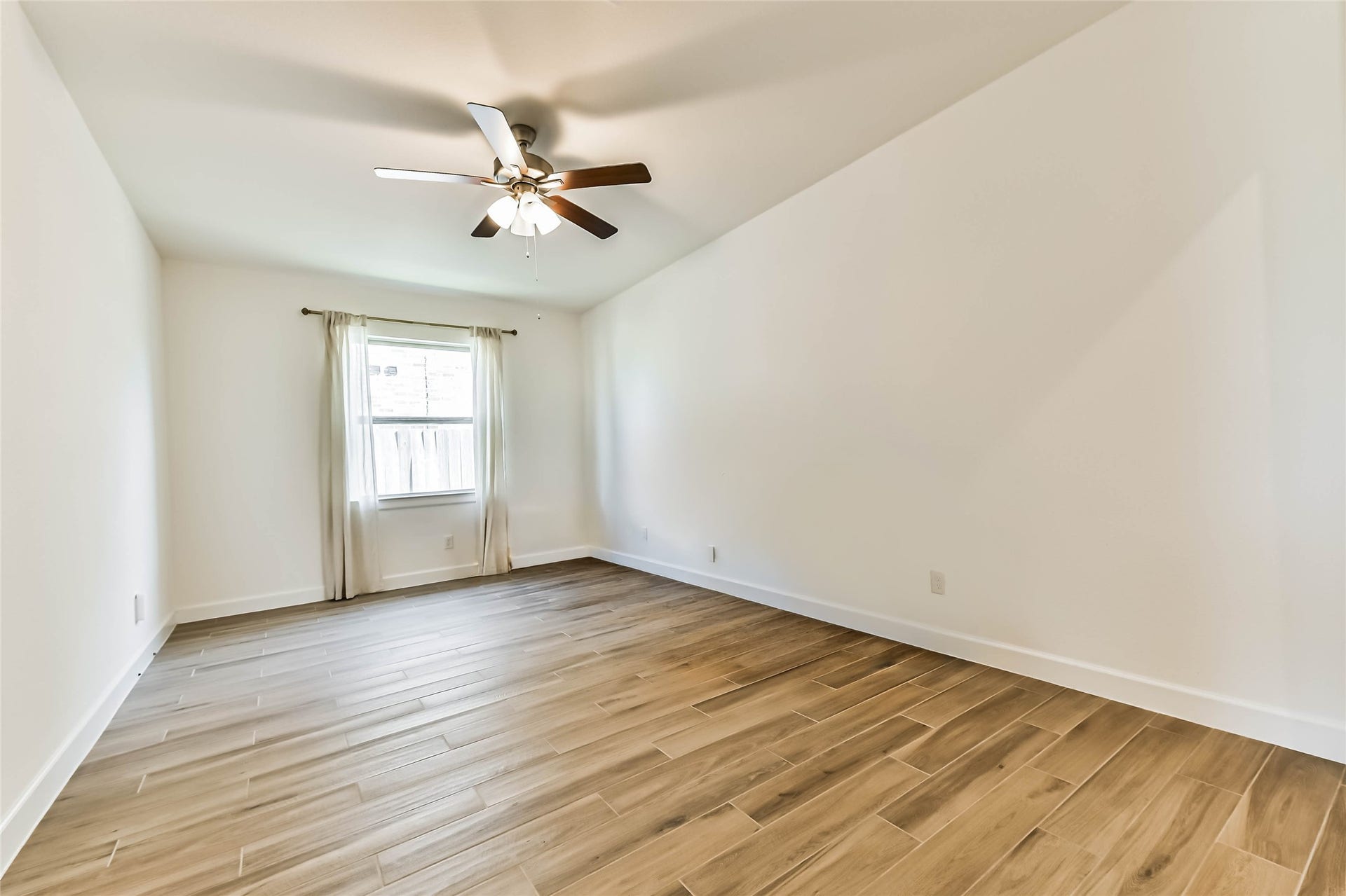 702 Campbell Drive, League City, TX 77573 Spacious living area featuring elegant wood-look flooring, a modern ceiling fan, and bright, neutral walls that enhance natural light.