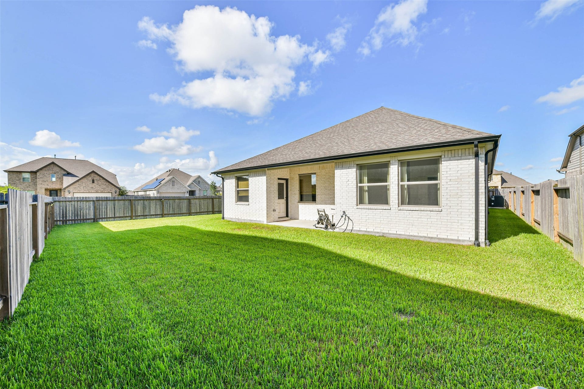 702 Campbell Drive, League City, TX 77573 Charming backyard featuring a spacious lawn, perfect for outdoor activities, enclosed by a wooden fence for privacy.