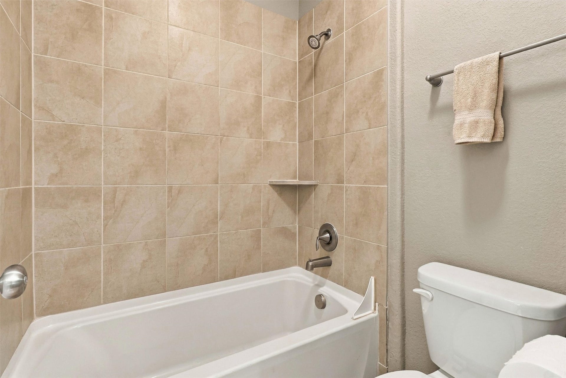 1407 Trails Of Katy Lane, Katy, TX 77494 This upstairs tub-and-shower combination offers a familiar, practical setup with a tiled surround and recessed storage niche. Its another example of the supporting spaces that make a large home comfortable to live in.