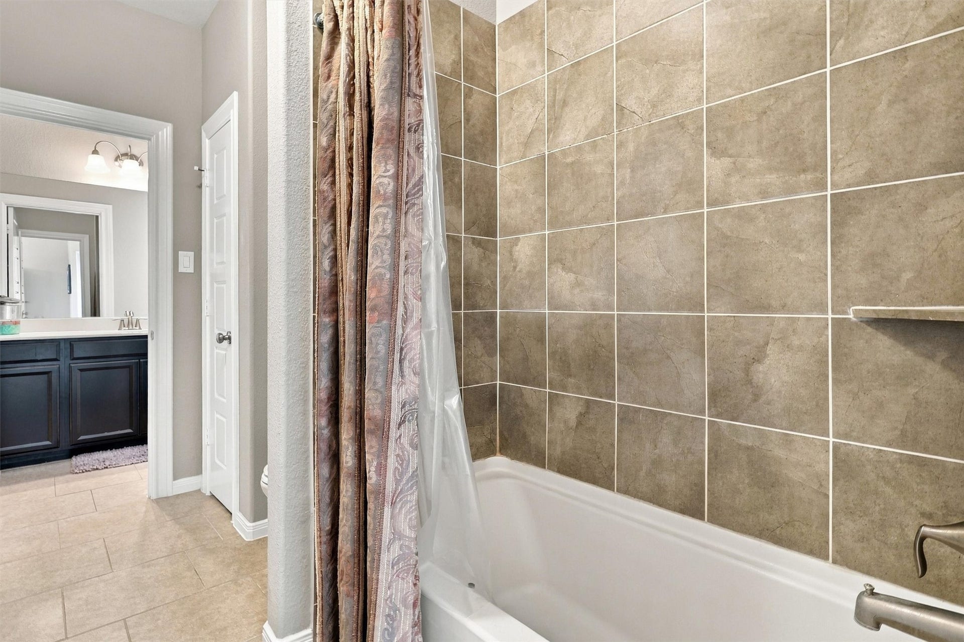 1407 Trails Of Katy Lane, Katy, TX 77494 A tiled tub-and-shower combination gives this upstairs bathroom everyday versatility. The separate bathing area complements the nearby vanity, creating a practical arrangement for household members and visiting guests.