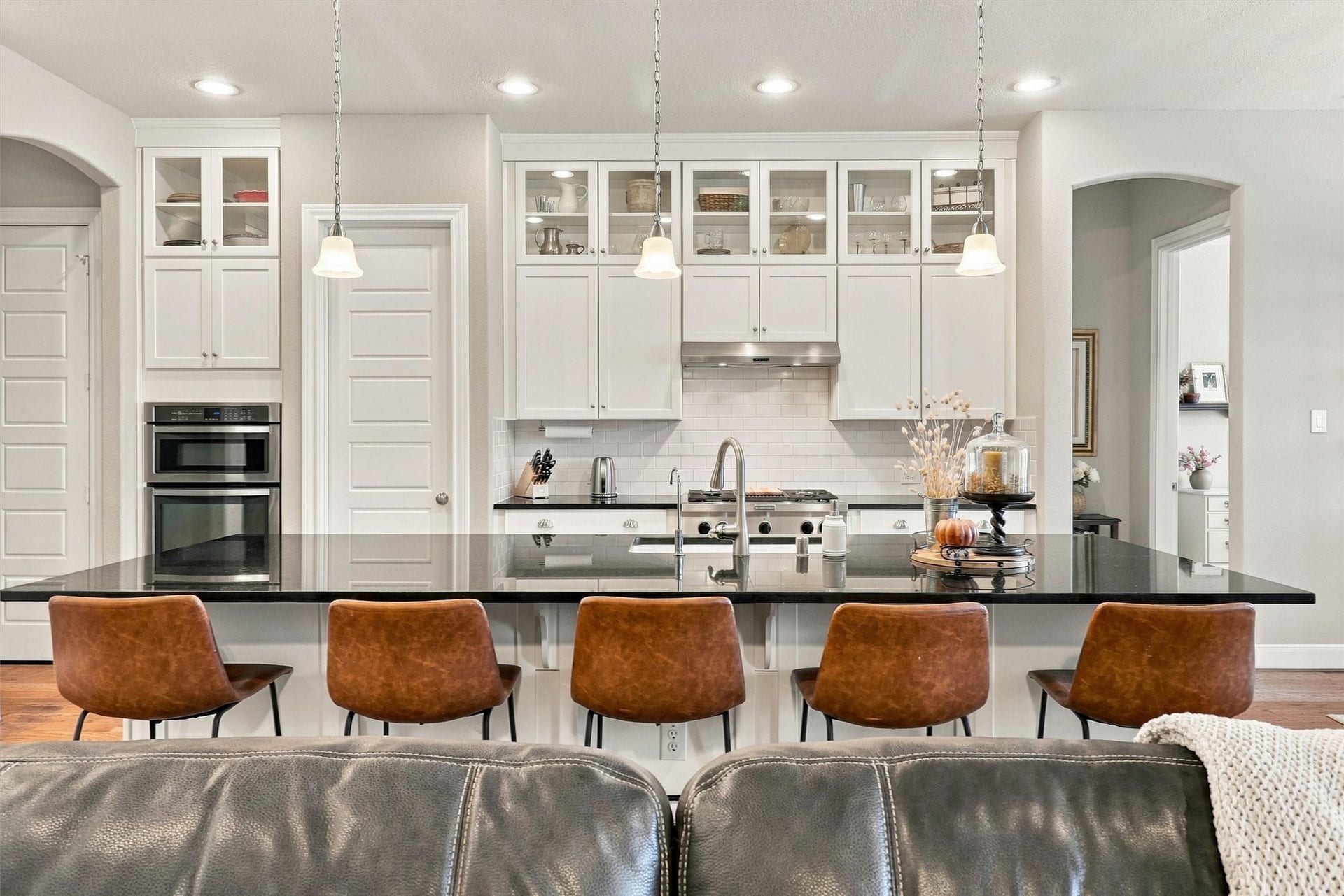 1407 Trails Of Katy Lane, Katy, TX 77494 White cabinetry, glass-front upper cabinets and contrasting dark countertops give the kitchen a polished presence. A gas cooktop, built-in oven and microwave support meal preparation, while the island keeps the cook connected to everyone nearby.