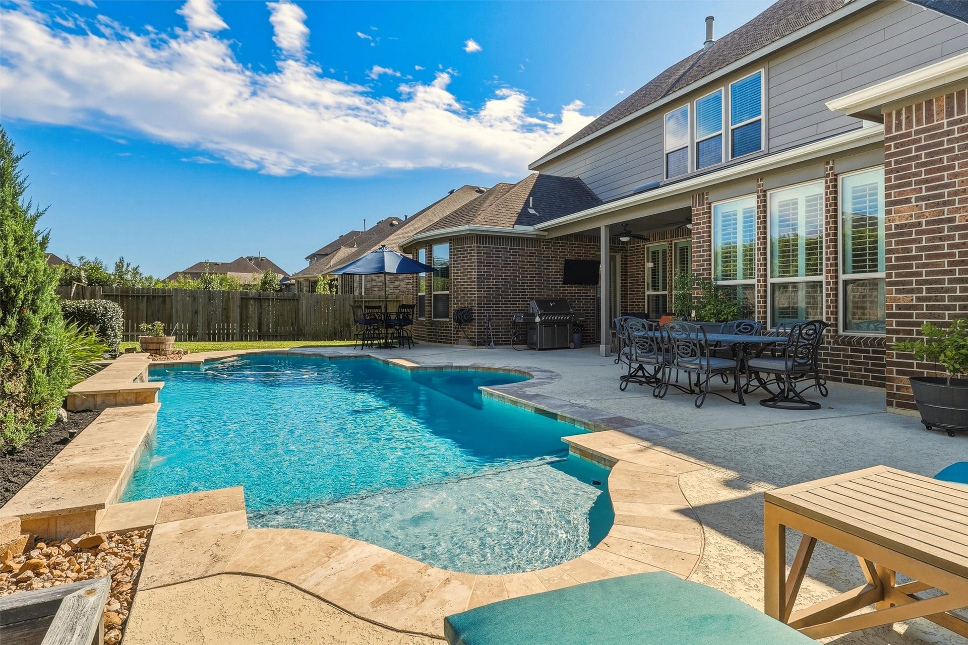 1407 Trails Of Katy Lane, Katy, TX 77494 The view back toward the home reveals how the pool, patio and rear living spaces work together. Its a setting that invites guests to move easily between conversation under cover, dining outside and time in the water.