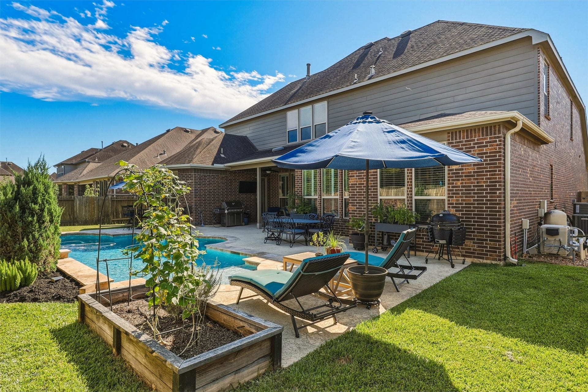 1407 Trails Of Katy Lane, Katy, TX 77494 Theres more to this backyard than the pool alone. This perspective shows the poolside setting alongside lawn, garden beds and landscaping, giving outdoor life several places to unfold, from lounging by the water to enjoying a little green space.