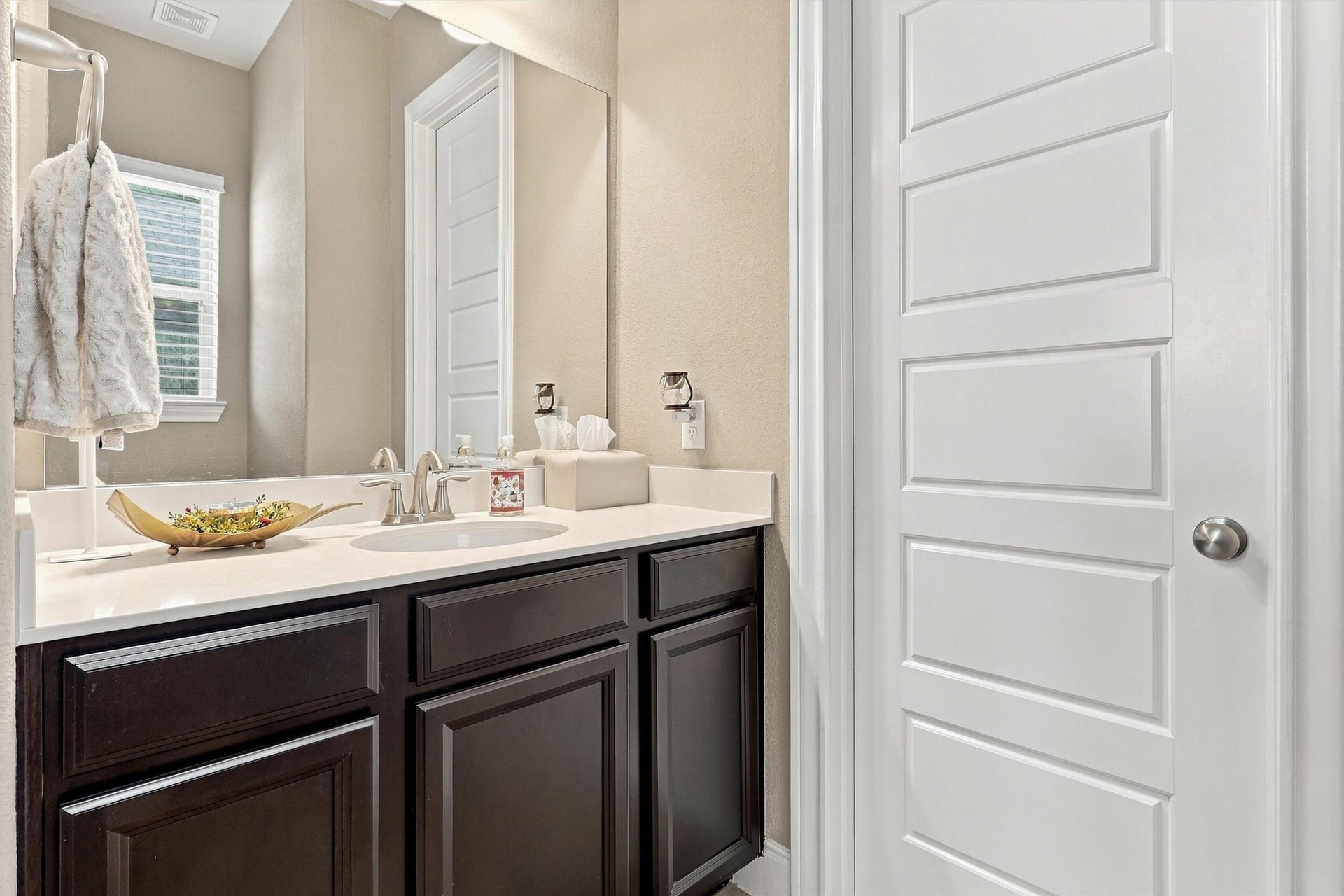 1407 Trails Of Katy Lane, Katy, TX 77494 A full bathroom on the first floor makes the downstairs secondary bedroom especially useful for guests. Dark cabinetry, a broad mirror and a window create a comfortable setting for getting ready without heading upstairs.