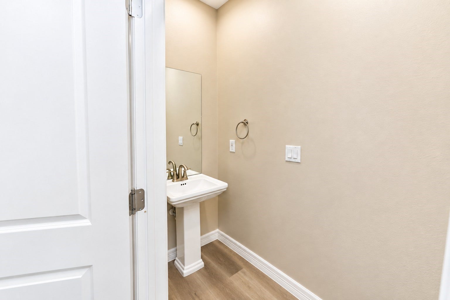 3248 Creekmont Drive, Houston, TX 77091 A cozy bathroom features a pedestal sink, sleek fixtures, and a large mirror, complemented by neutral walls and warm wood flooring.