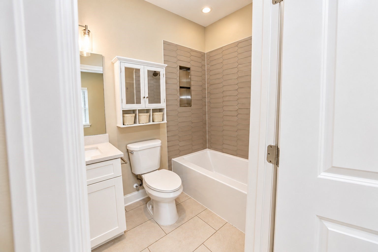 3248 Creekmont Drive, Houston, TX 77091 Elegant bathroom featuring a modern tub with textured tile surround, sleek vanity, and ample storage with a mirrored cabinet.