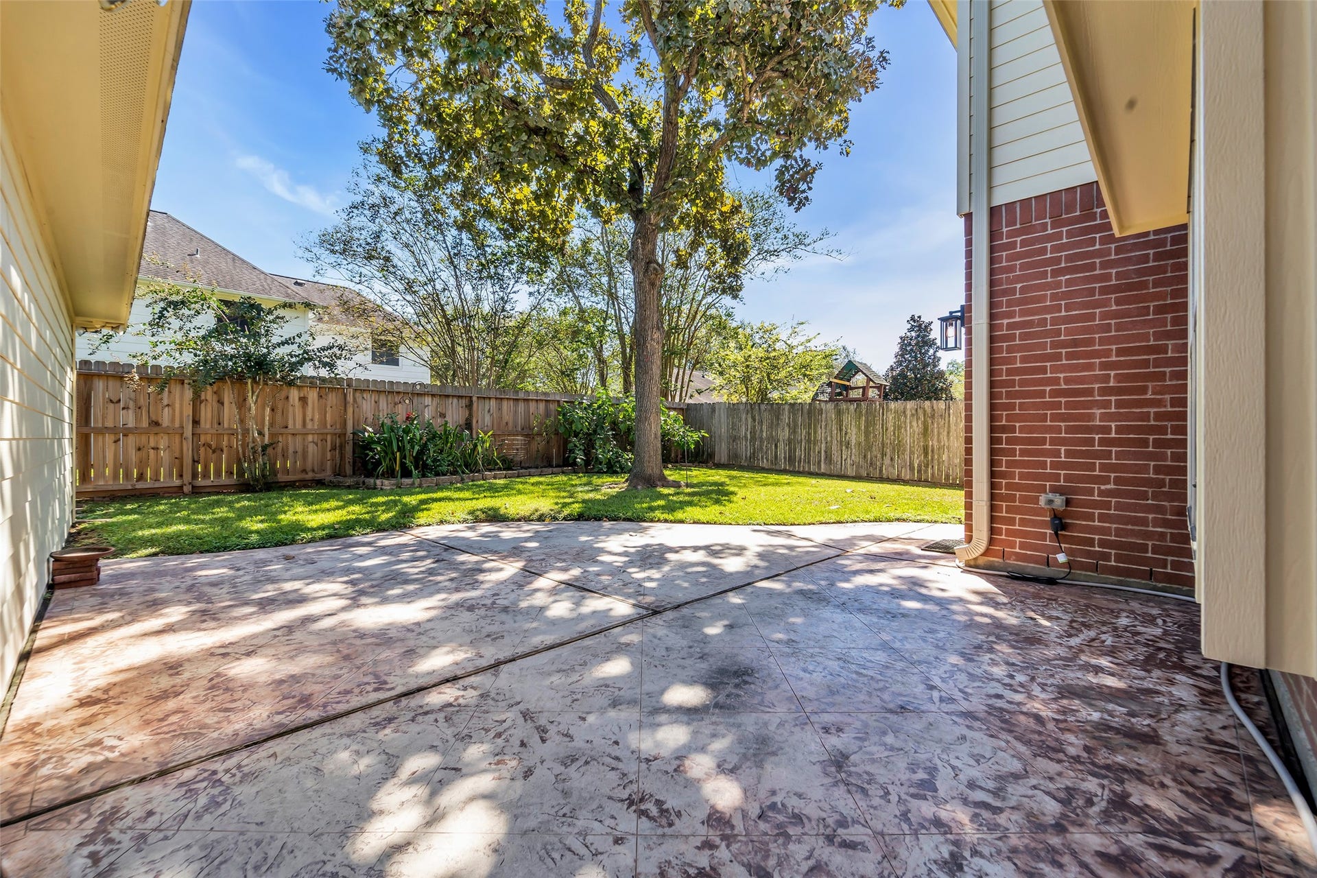 1344 Coleman Boylan Drive, League City, TX 77573 Charming backyard featuring a spacious patio with stamped concrete, ideal for outdoor gatherings, surrounded by lush greenery and mature trees for added privacy.