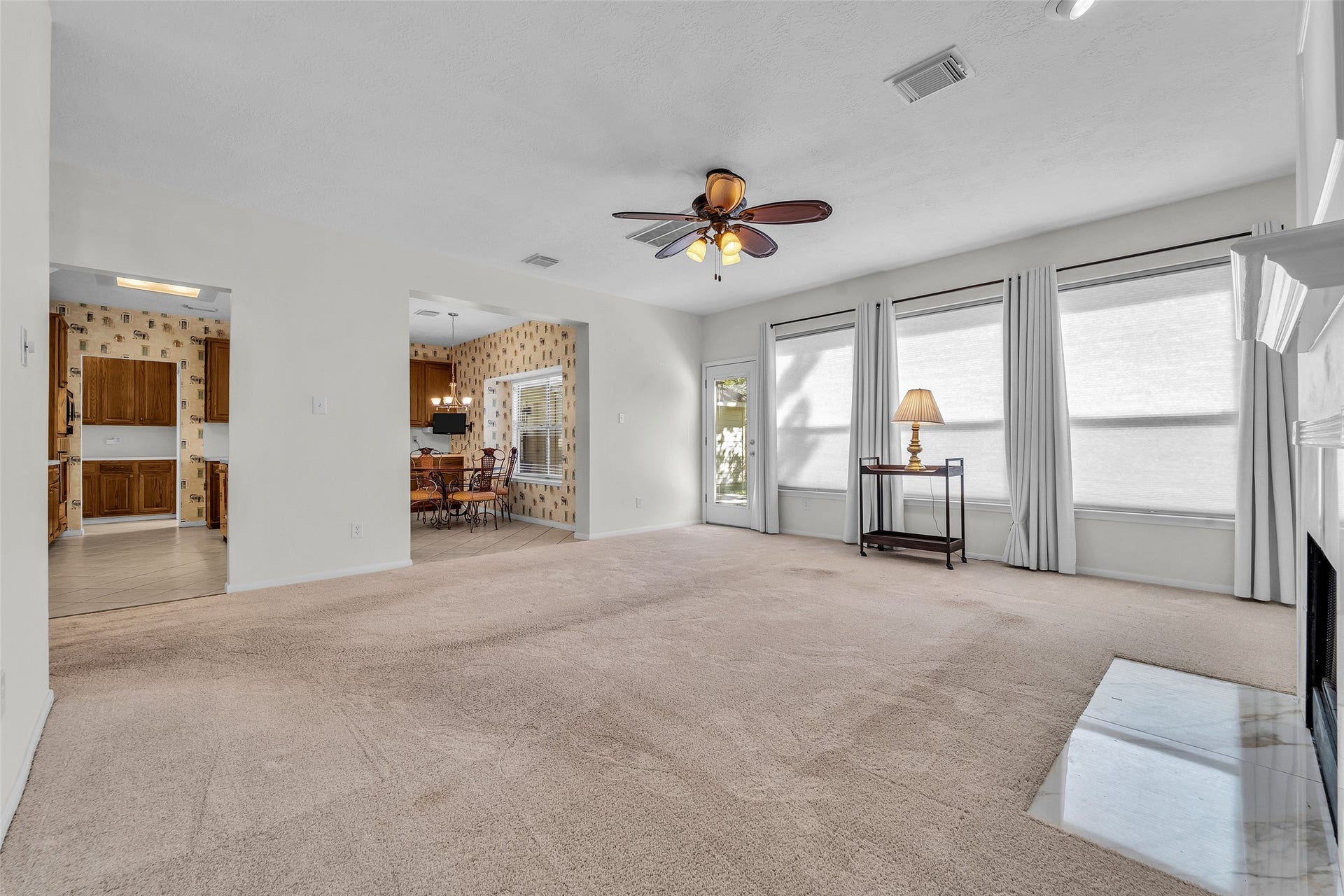 1344 Coleman Boylan Drive, League City, TX 77573 Spacious living area with abundant natural light, a cozy fireplace, and an adjacent dining space leading to a charming kitchen.