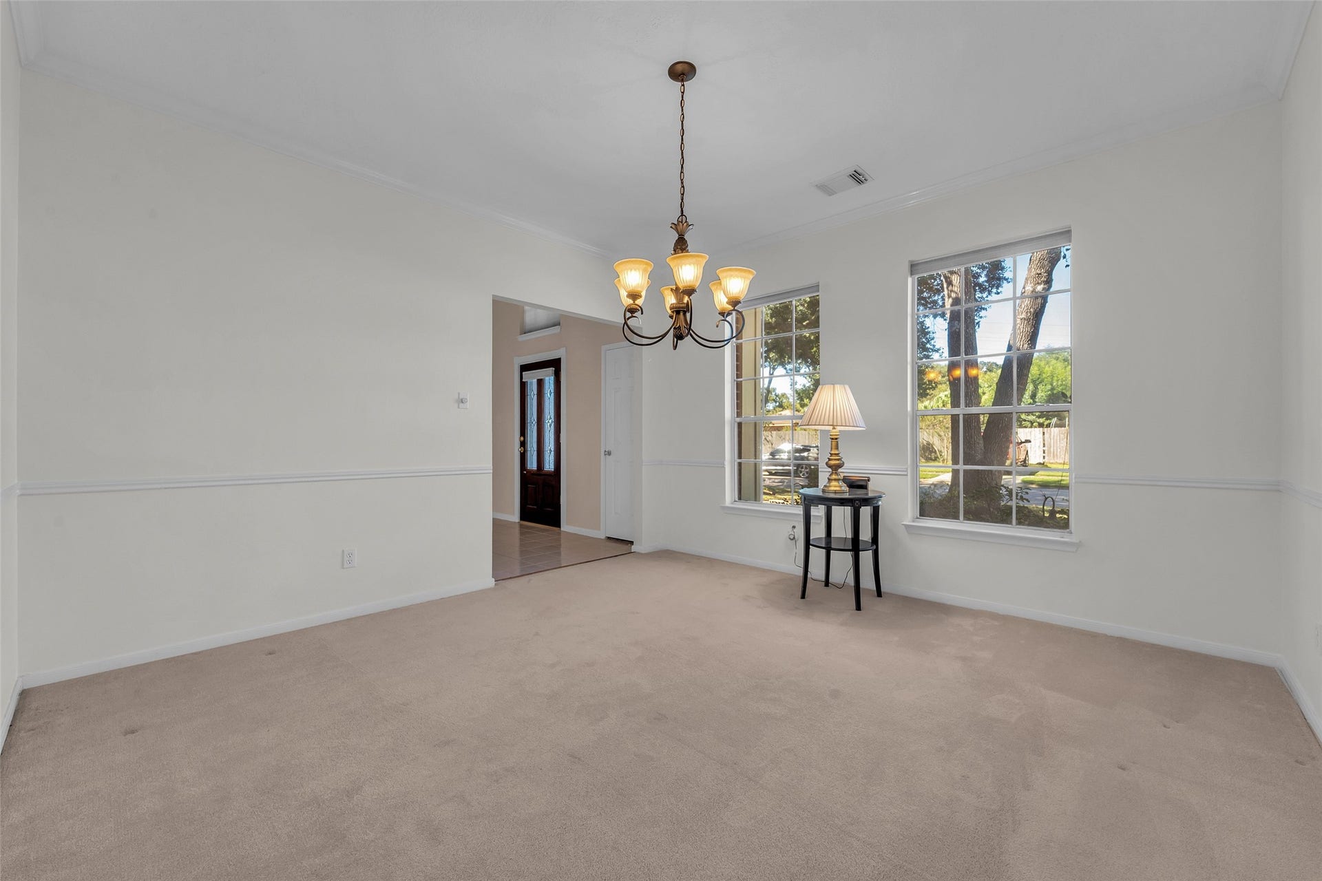 1344 Coleman Boylan Drive, League City, TX 77573 Bright dining area with a classic chandelier, neutral walls, and large windows offering a serene view of the garden.