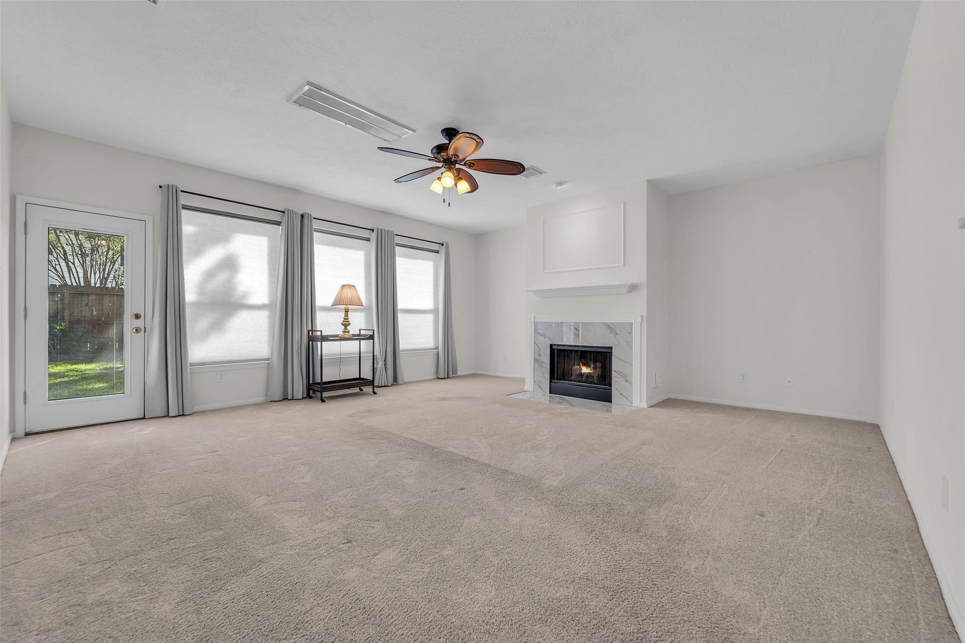 1344 Coleman Boylan Drive, League City, TX 77573 Spacious living room featuring a cozy fireplace, large windows for natural light, and direct access to the outdoor space through a glass door.