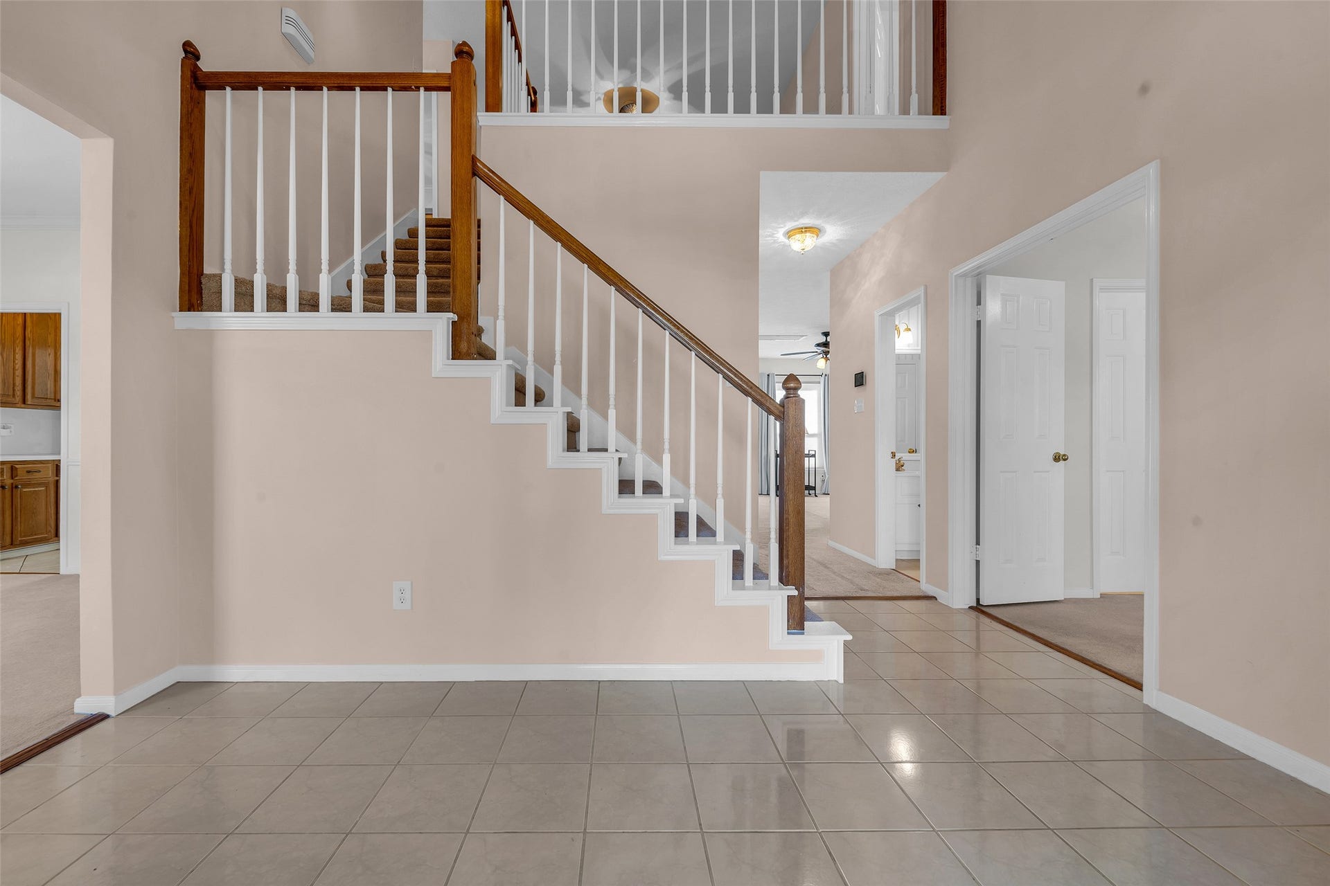 1344 Coleman Boylan Drive, League City, TX 77573 A welcoming foyer with tiled flooring leads to a staircase featuring elegant wooden railing, offering access to a spacious upper level. Adjacent rooms include a bright kitchen and cozy living area, perfect for family gatherings.