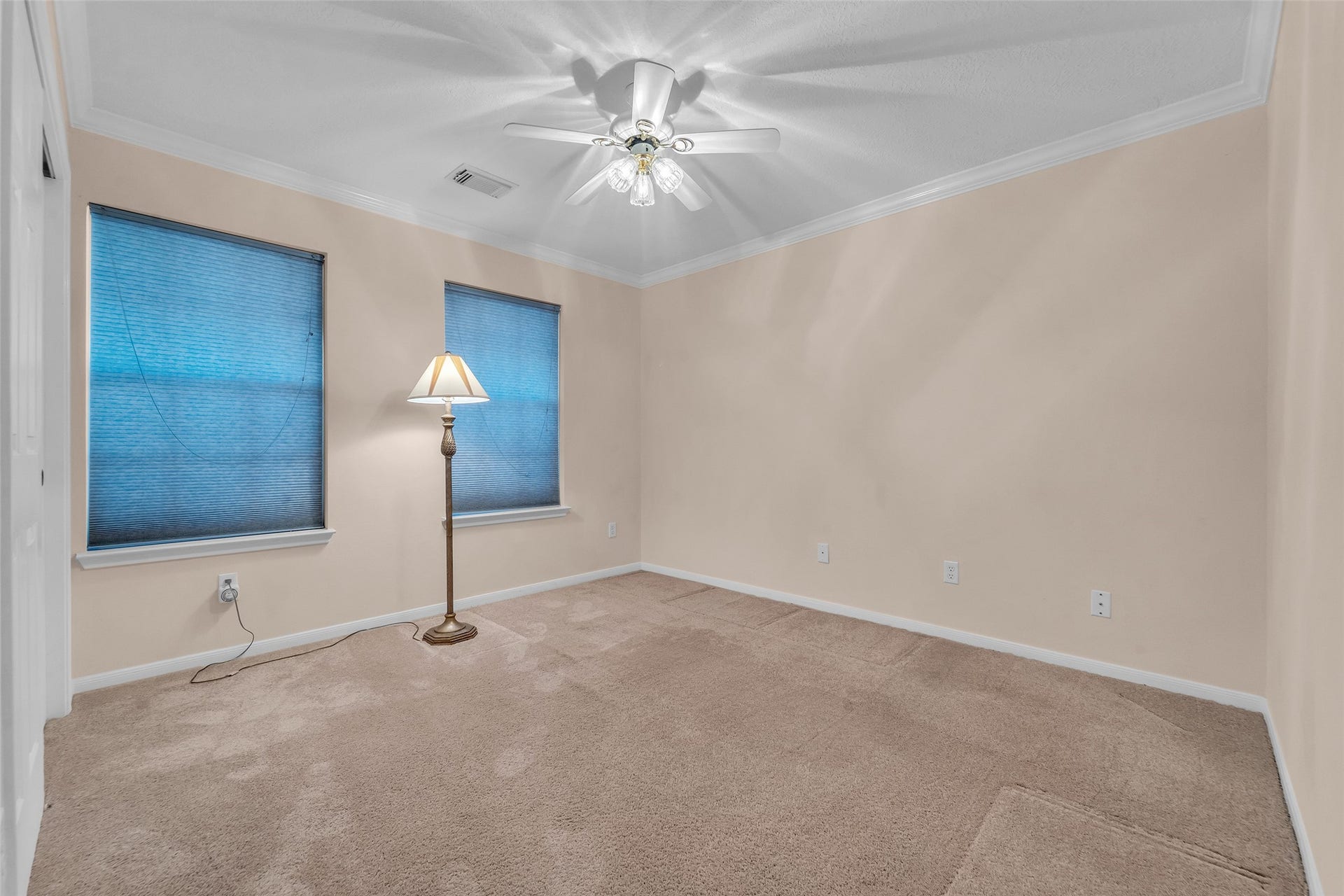 1344 Coleman Boylan Drive, League City, TX 77573 Spacious bedroom with neutral walls, carpet flooring, and two large windows providing natural light, complemented by a ceiling fan.