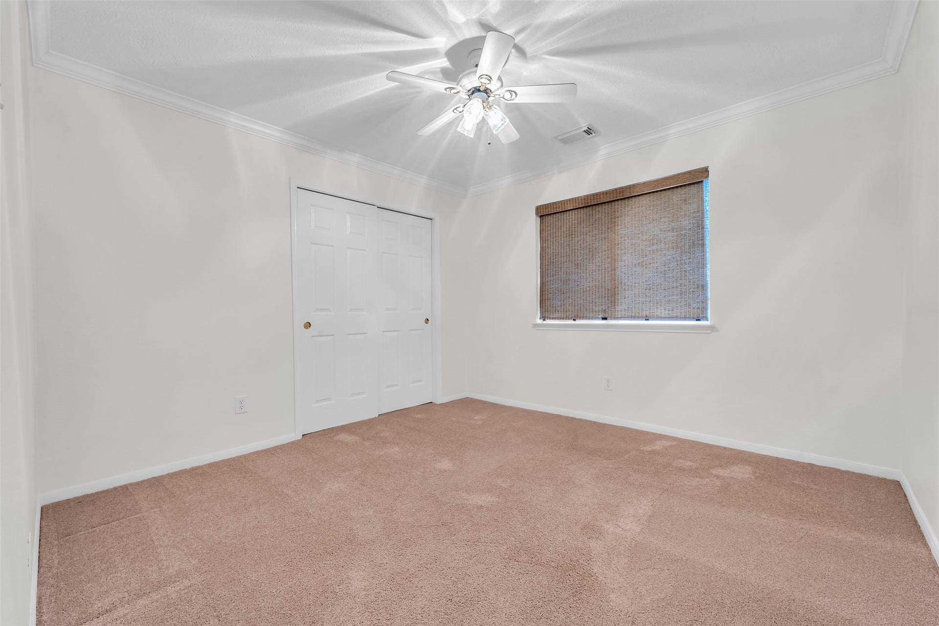1344 Coleman Boylan Drive, League City, TX 77573 Spacious bedroom with plush carpeting, a ceiling fan, and ample closet space, enhanced by natural light from a cozy window with blinds.
