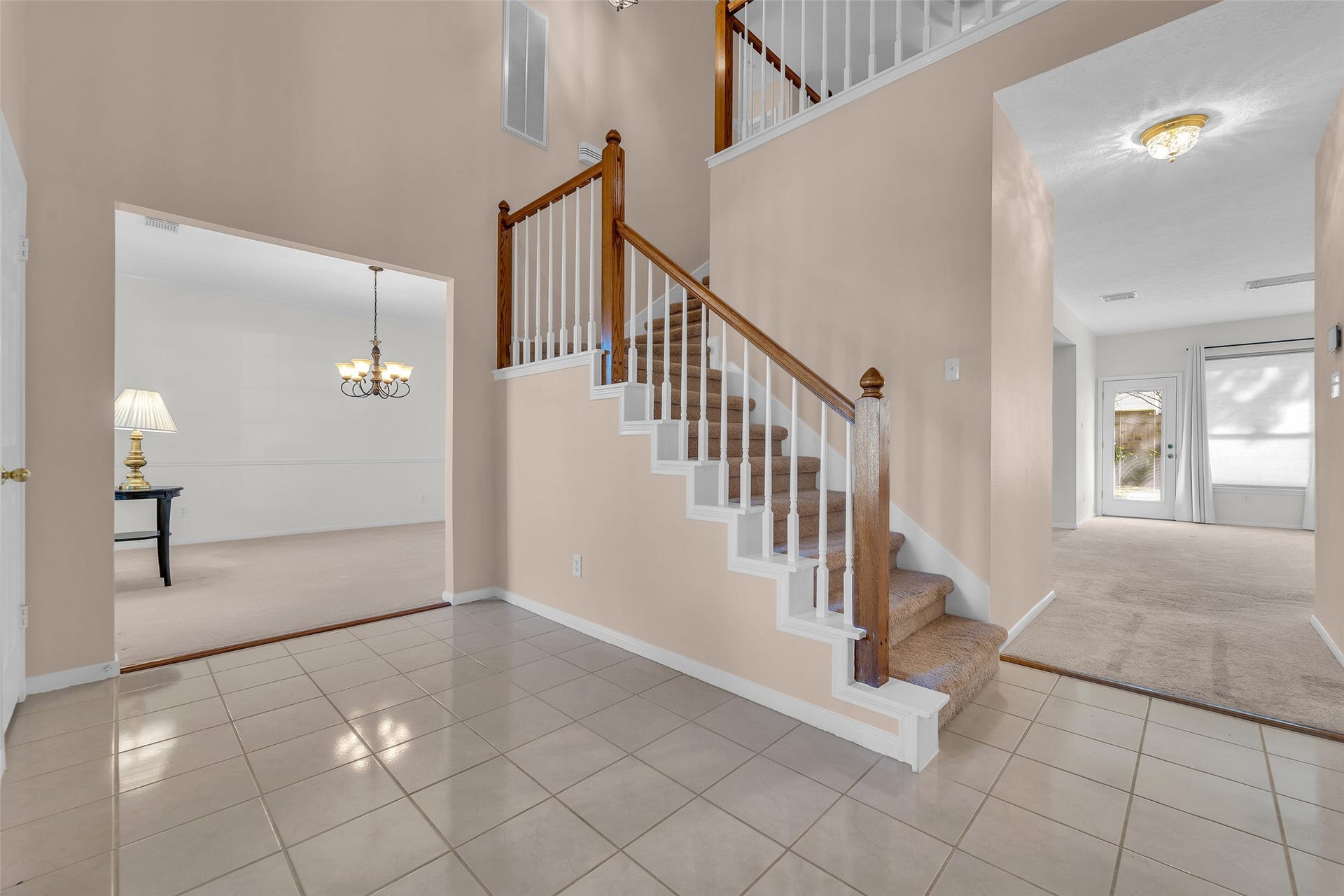 1344 Coleman Boylan Drive, League City, TX 77573 Spacious entryway features elegant tile flooring and a carpeted staircase with wooden accents, leading to well-lit living areas and a cozy dining room.
