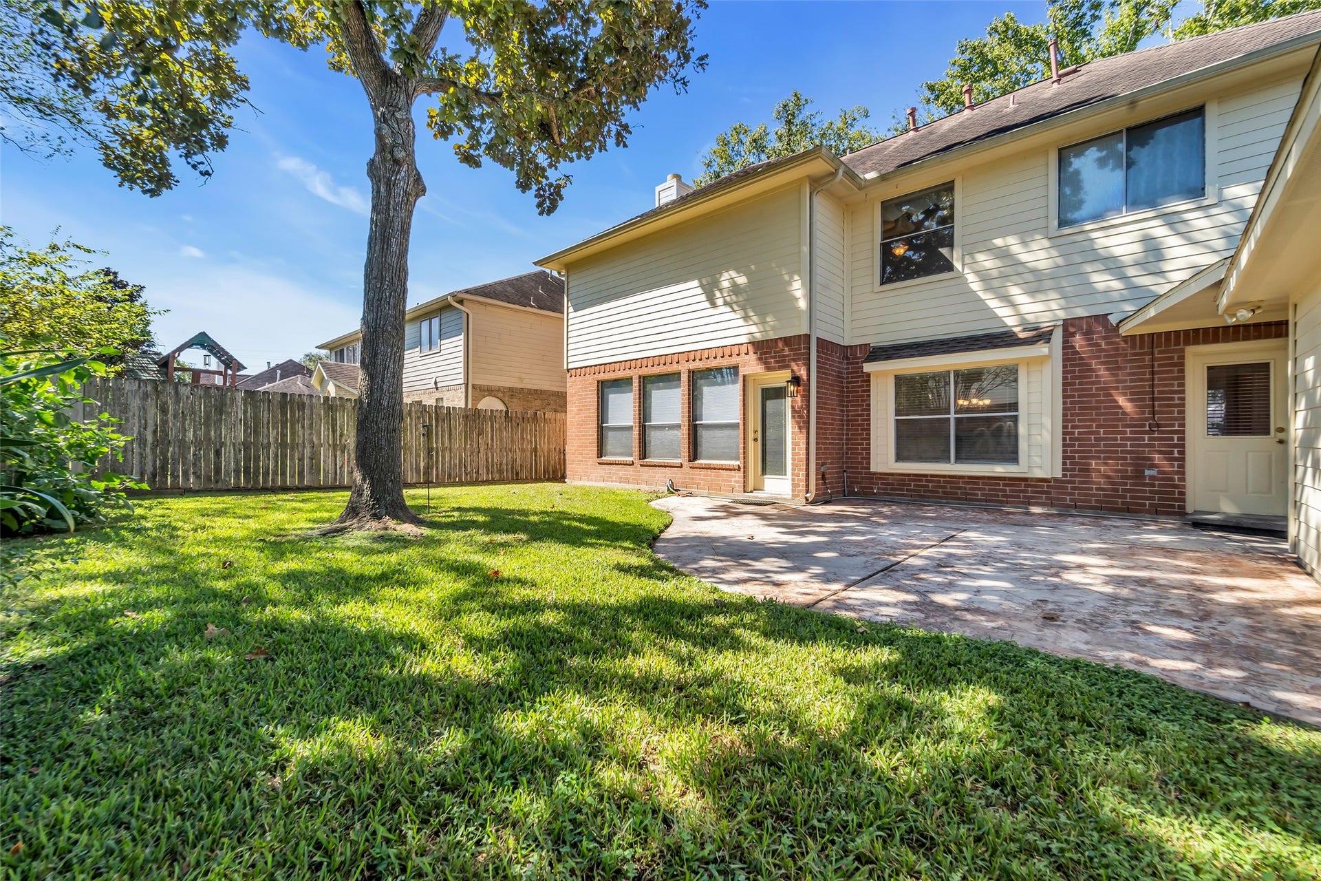1344 Coleman Boylan Drive, League City, TX 77573 Spacious backyard with a charming patio, perfect for outdoor gatherings, surrounded by lush greenery and mature trees for added privacy.