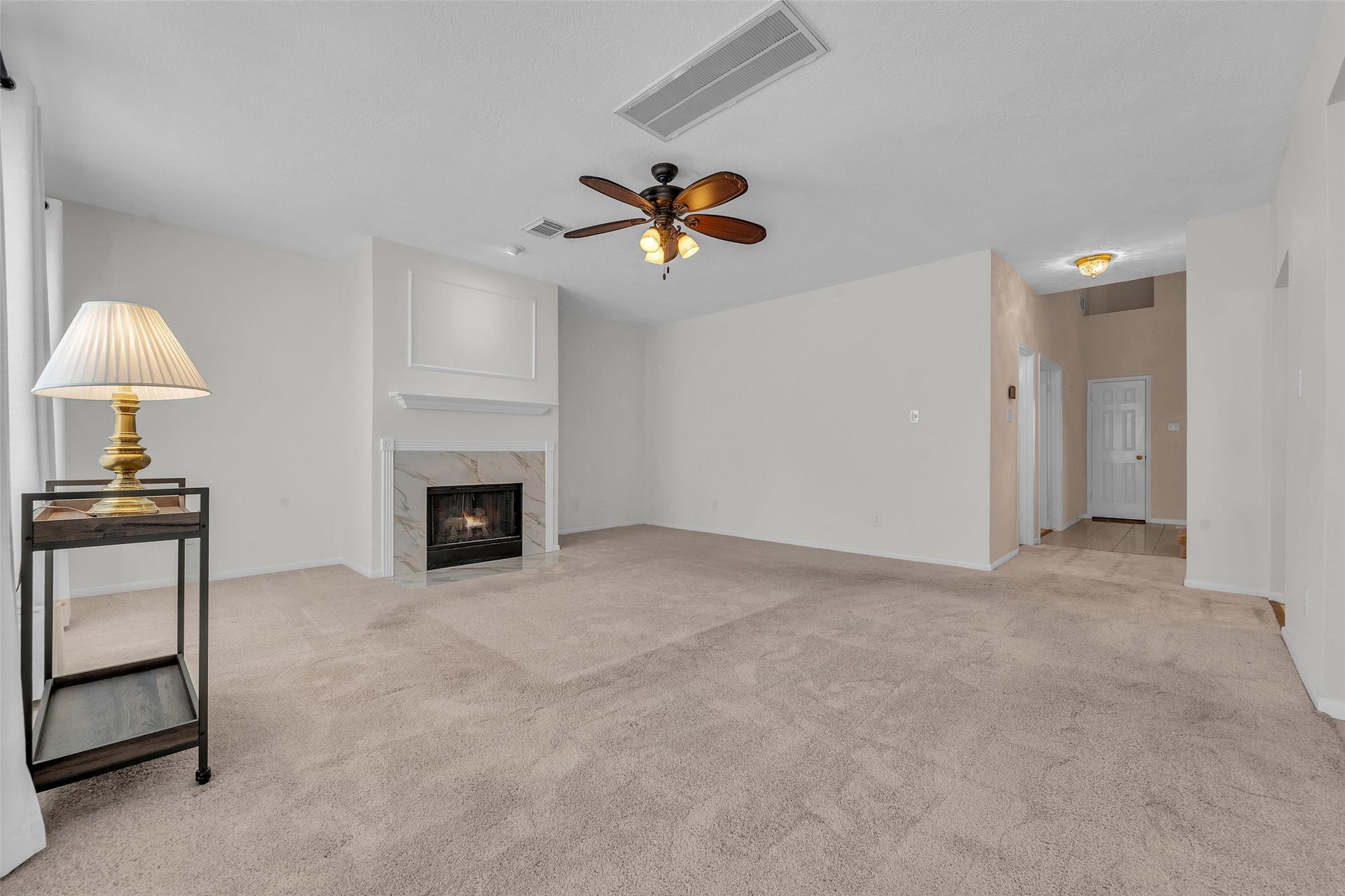 1344 Coleman Boylan Drive, League City, TX 77573 Spacious living room features a cozy fireplace, neutral carpeting, and a ceiling fan, offering a warm and inviting atmosphere.