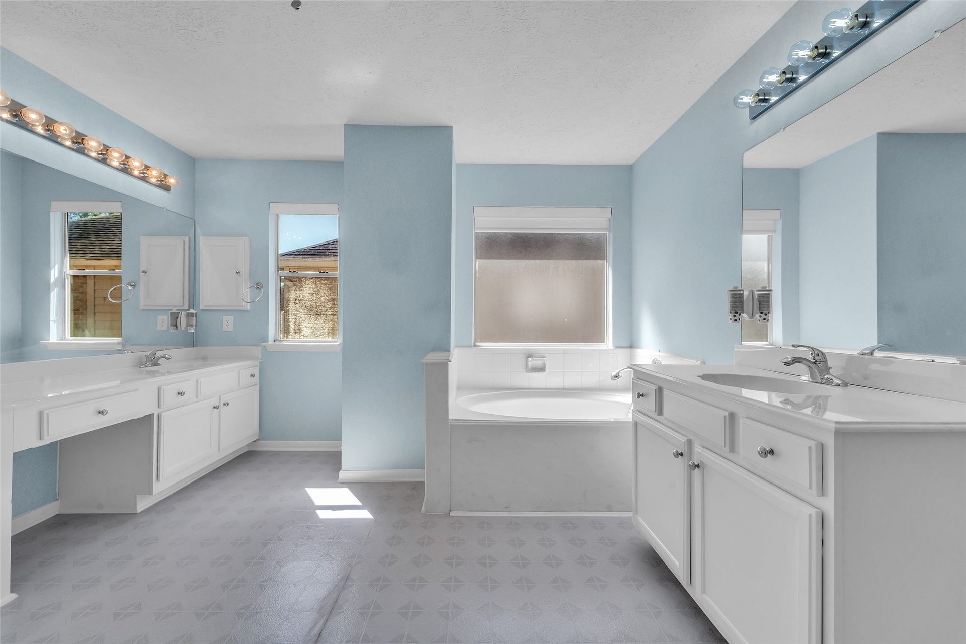 1344 Coleman Boylan Drive, League City, TX 77573 Spacious bathroom featuring dual vanities, a large soaking tub, and ample natural light, all set against soothing blue walls.