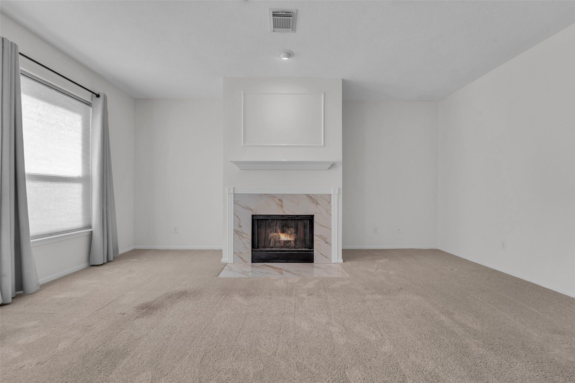 1344 Coleman Boylan Drive, League City, TX 77573 Spacious living room featuring a cozy fireplace with elegant marble detailing, complemented by soft carpet and abundant natural light from a large window.