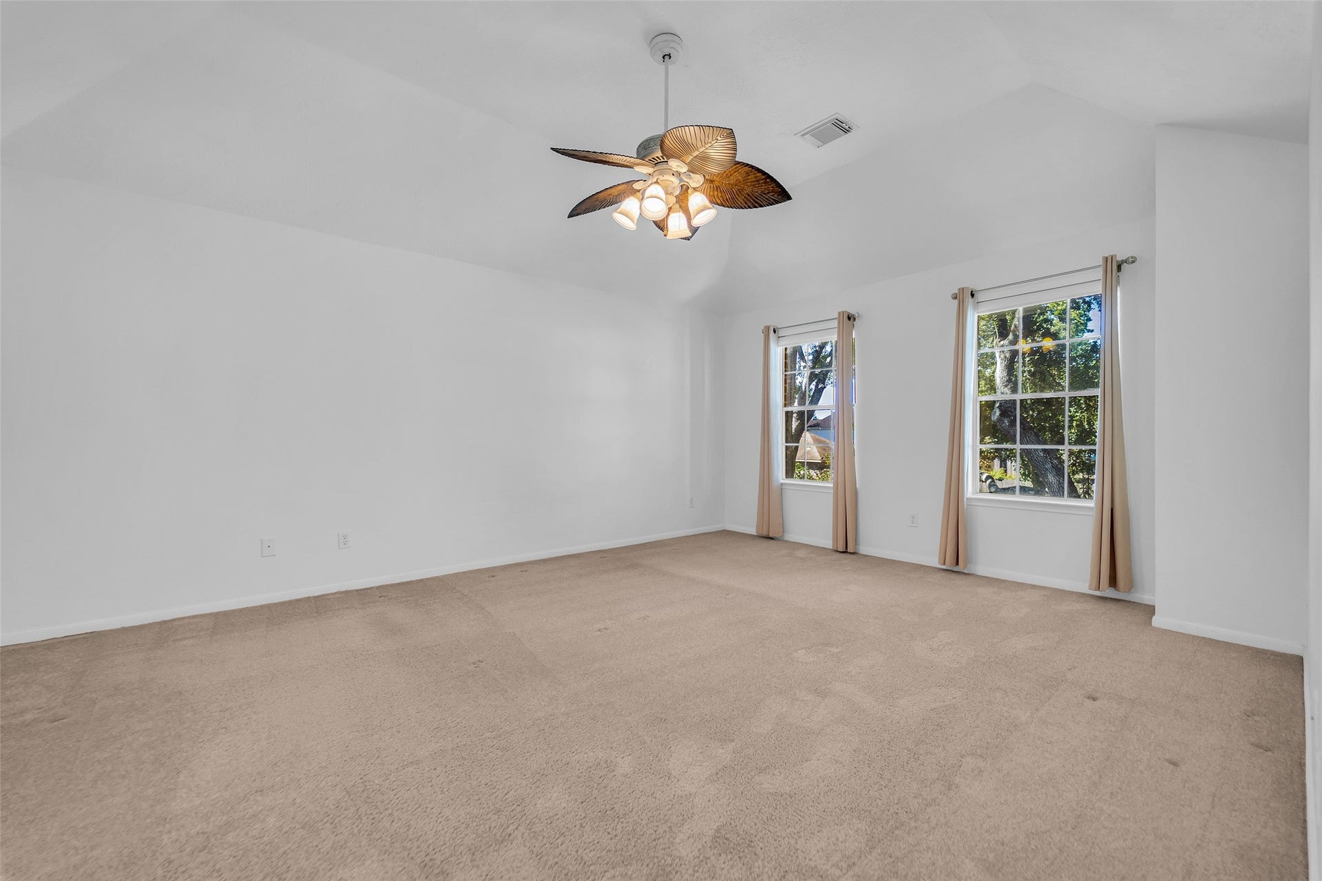 1344 Coleman Boylan Drive, League City, TX 77573 Spacious bedroom with neutral carpet, large windows for natural light, and a stylish ceiling fan.