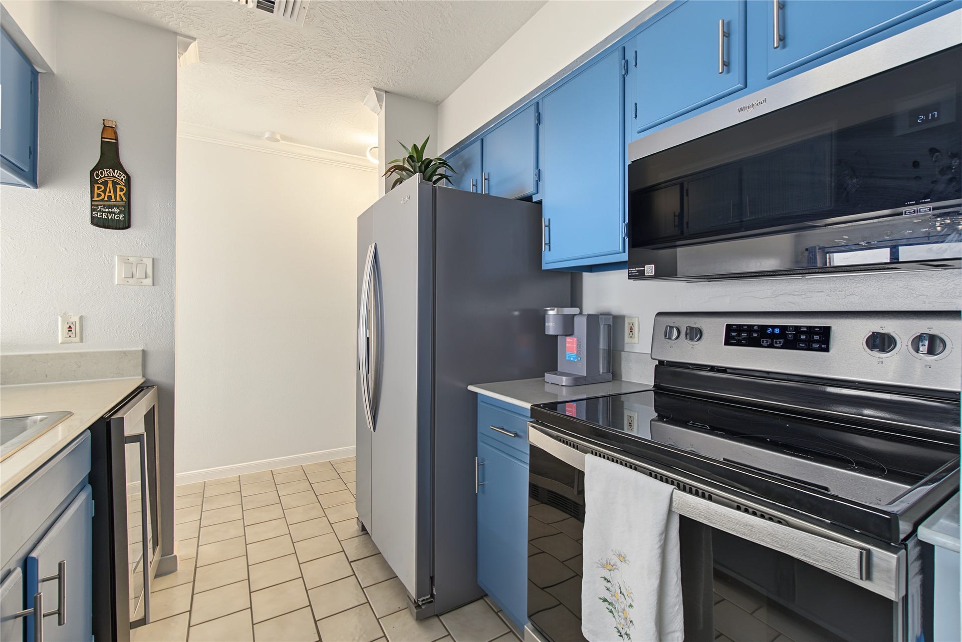 Stainless steel appliances, including the refrigerator, complement the kitchen's distinctive blue cabinetry.