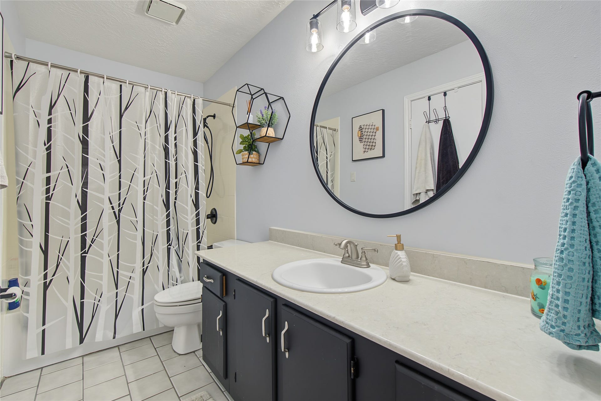Full bathroom with generous vanity counter space, decorative mirror, and tub/shower combination.