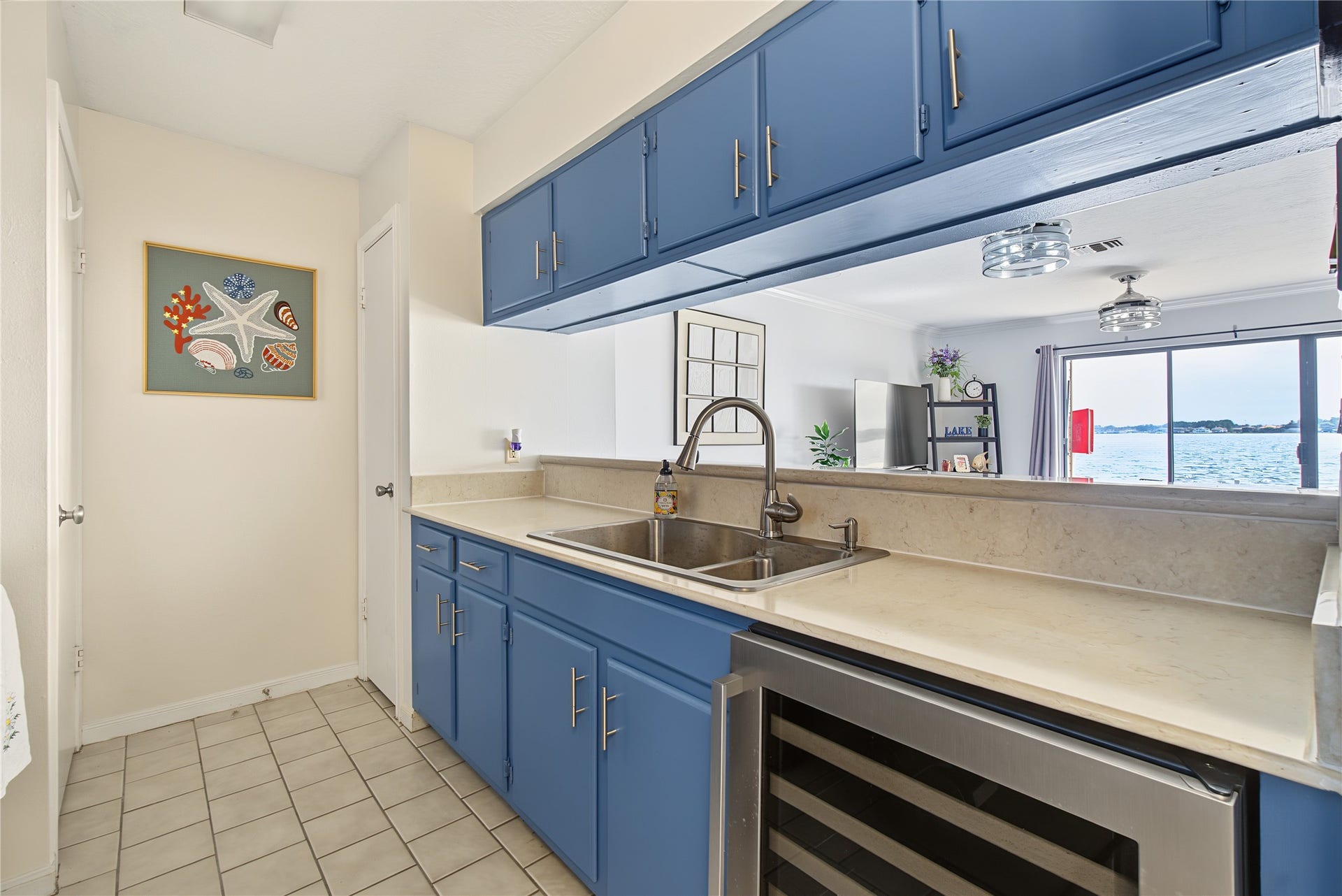 Efficient kitchen design with cheerful blue cabinetry, ample storage, and convenient serving pass-through.