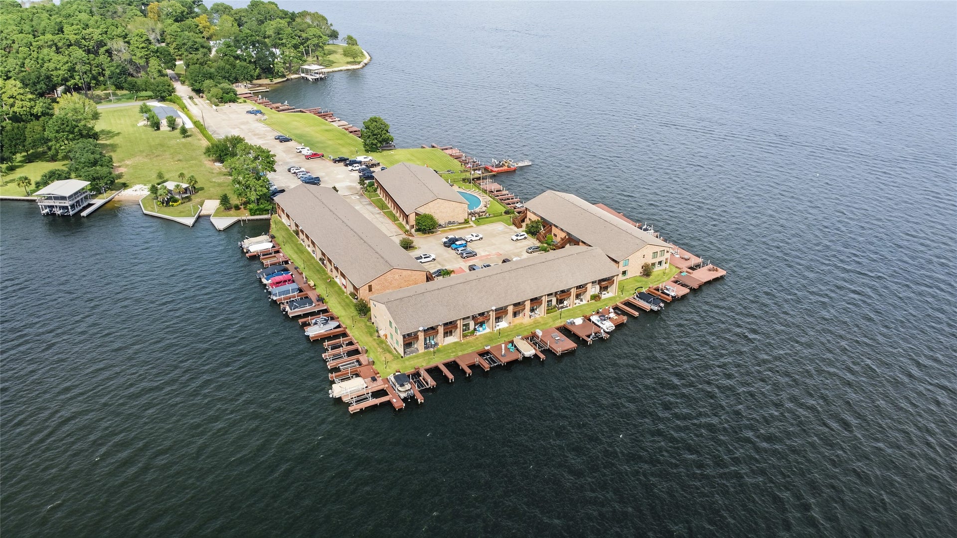 Expansive aerial view of the condominium complex surrounded by sparkling lake waters and private boat docks.