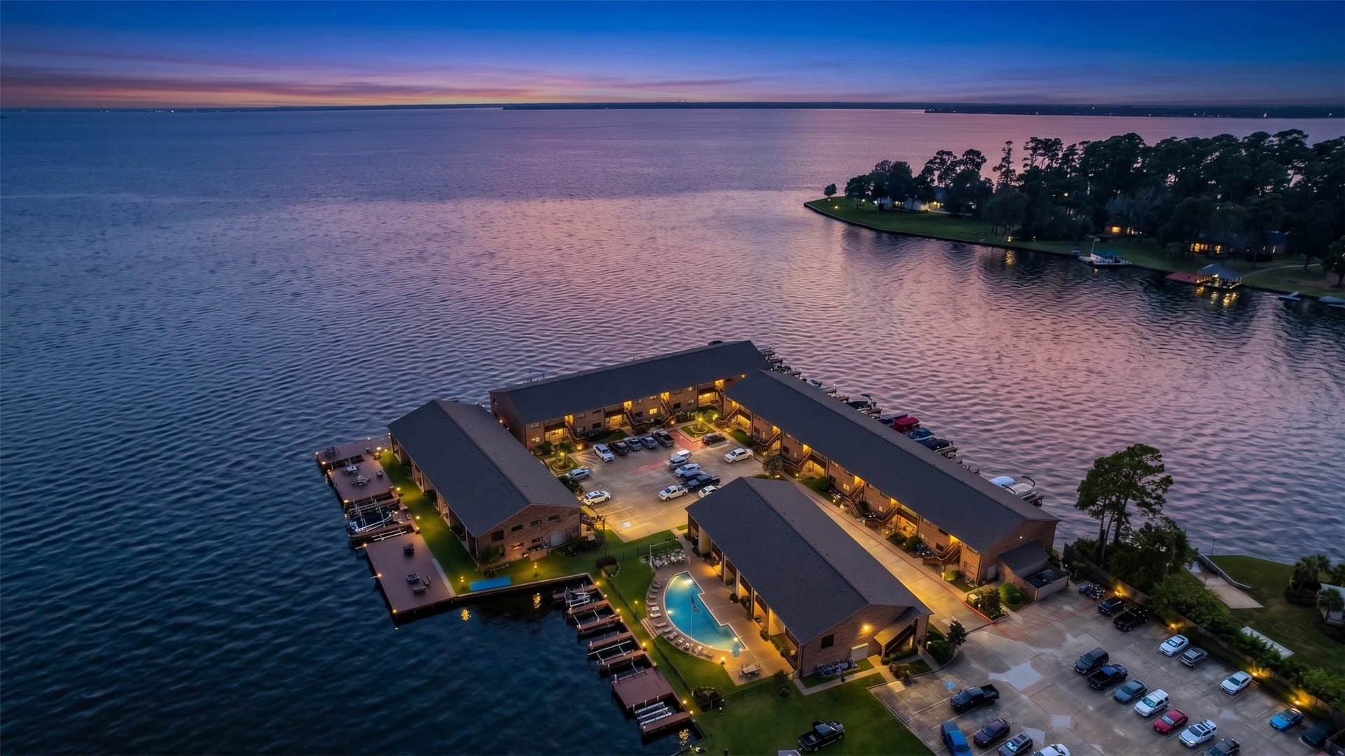 Spectacular twilight aerial view captures the illuminated waterfront community against a breathtaking Lake Conroe sunset.