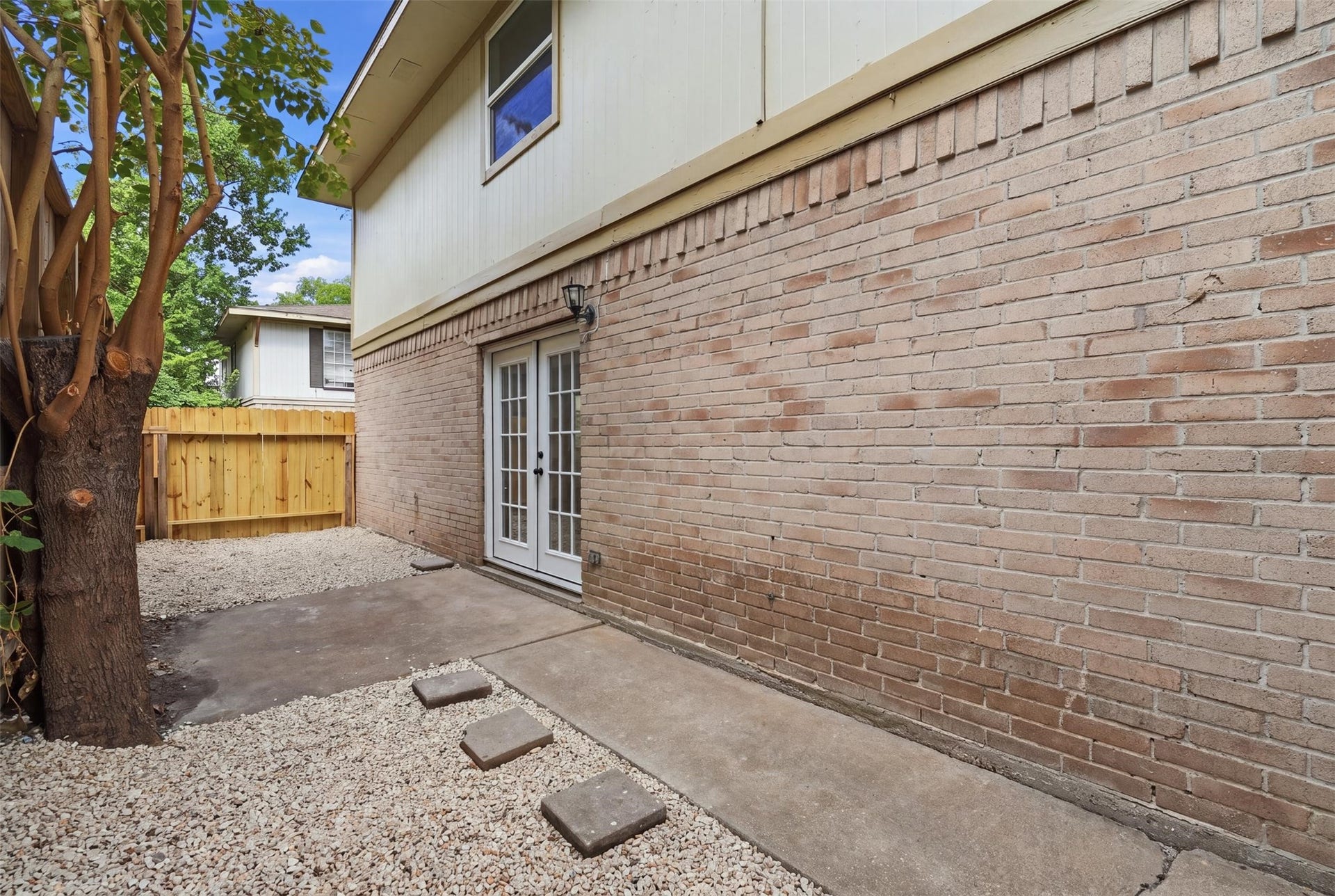 1936 Upland Drive, Houston, TX 77043 Charming private patio with French doors, brick exterior, and a cozy space with gravel and stepping stones, perfect for outdoor relaxation.