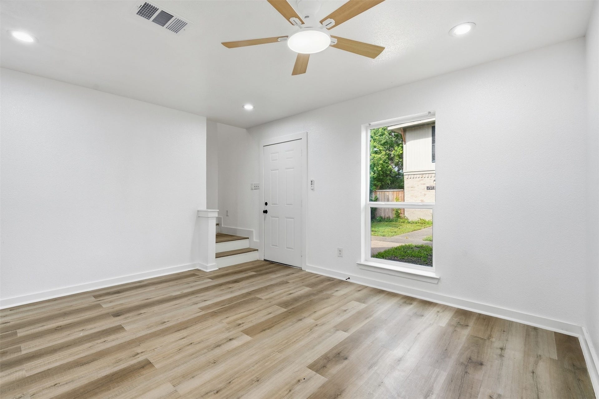 1936 Upland Drive, Houston, TX 77043 Bright and inviting room featuring elegant wood-look flooring, a modern ceiling fan, and ample natural light from a large window, creating a warm and welcoming atmosphere.