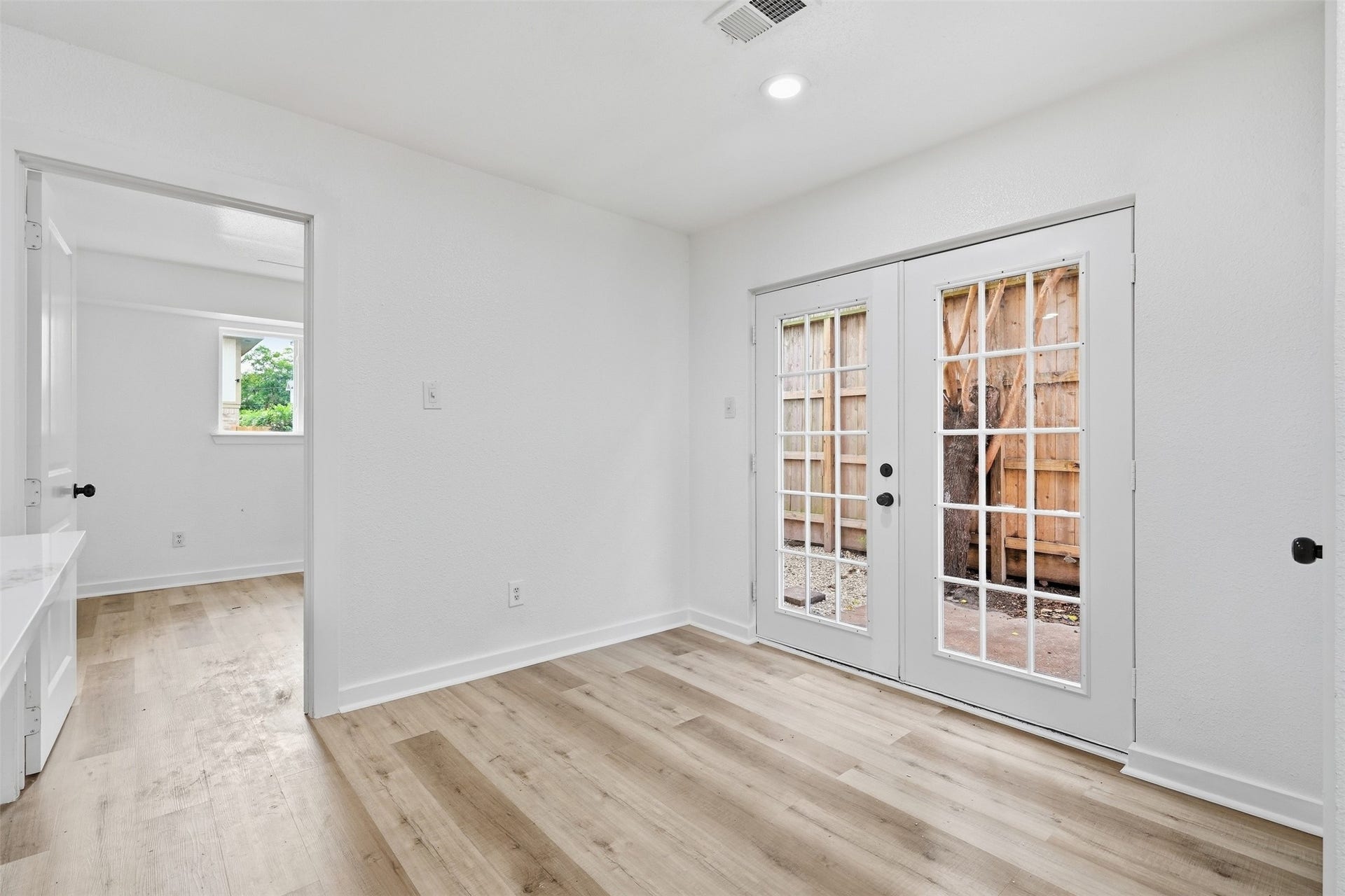 1936 Upland Drive, Houston, TX 77043 Bright and inviting room featuring elegant French doors opening to a private outdoor space, complemented by sleek hardwood floors and clean, modern finishes.