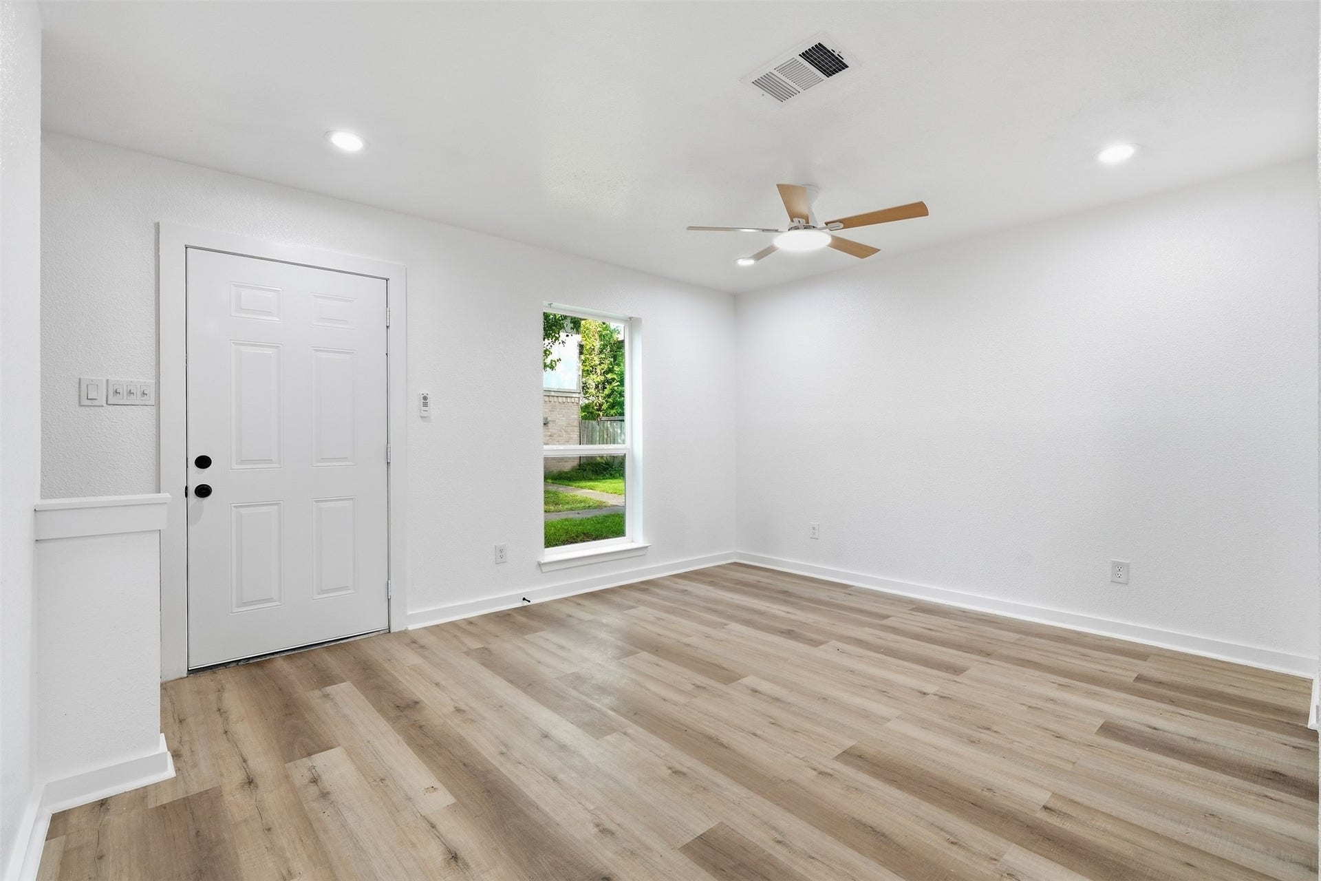 1936 Upland Drive, Houston, TX 77043 Bright and airy living space featuring fresh white walls, sleek wood flooring, recessed lighting, and a modern ceiling fan, perfect for a welcoming entrance.
